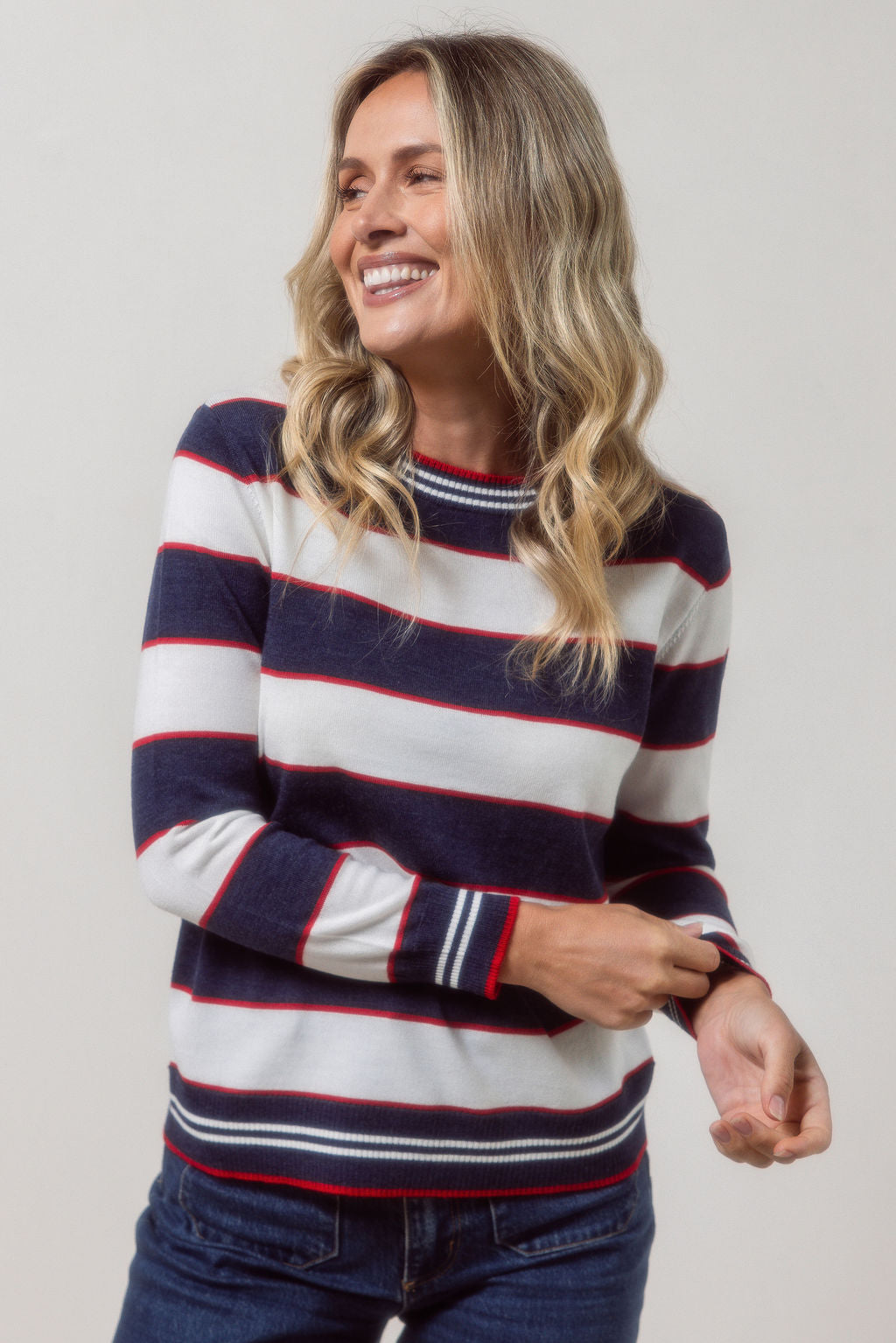 Woman wearing a striped merino wool See Saw sweater with a plain background