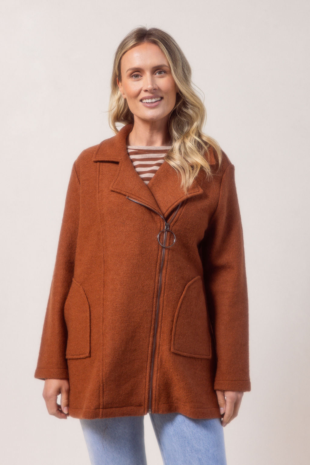 Woman wearing a copper See Saw boiled wool coat against a plain background