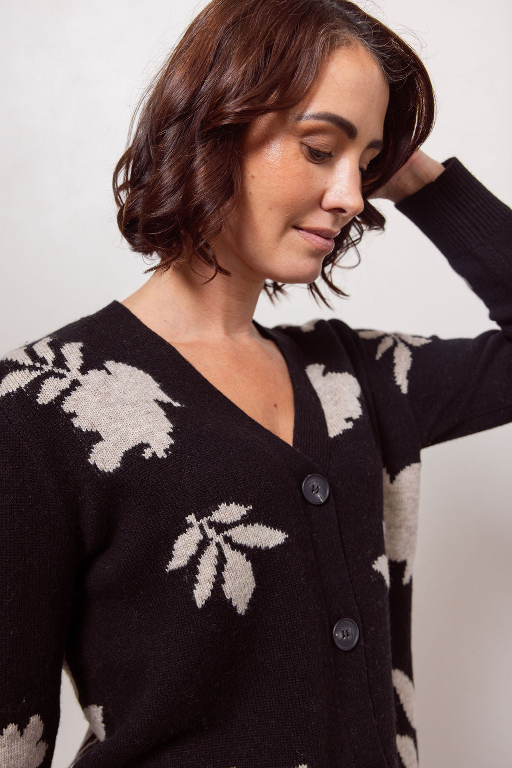 Woman wearing a black See Saw cardigan with white floral patterns against a plain background