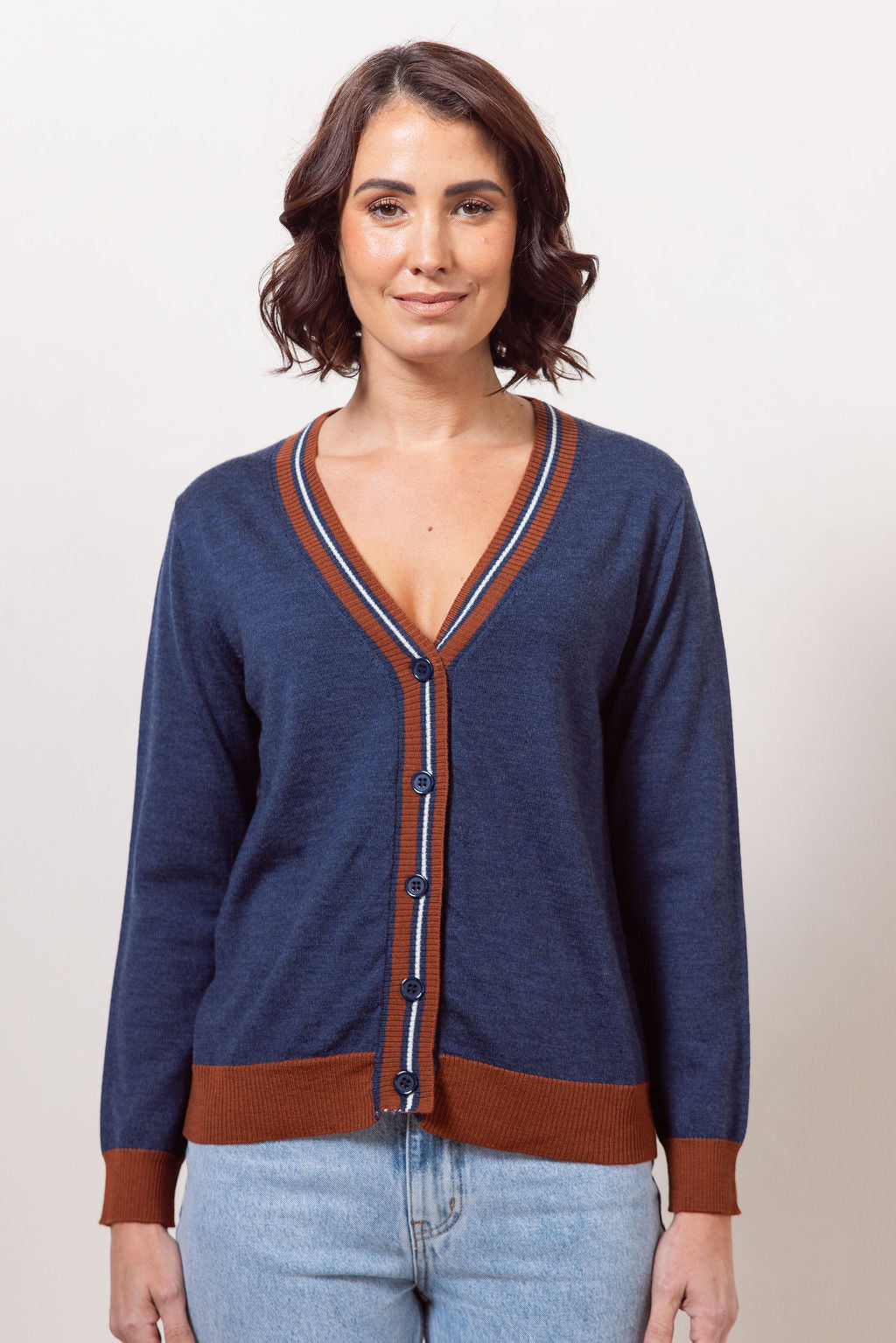Woman wearing an Indigo See Saw Merino Wool cardigan with blue and red accents on a plain background