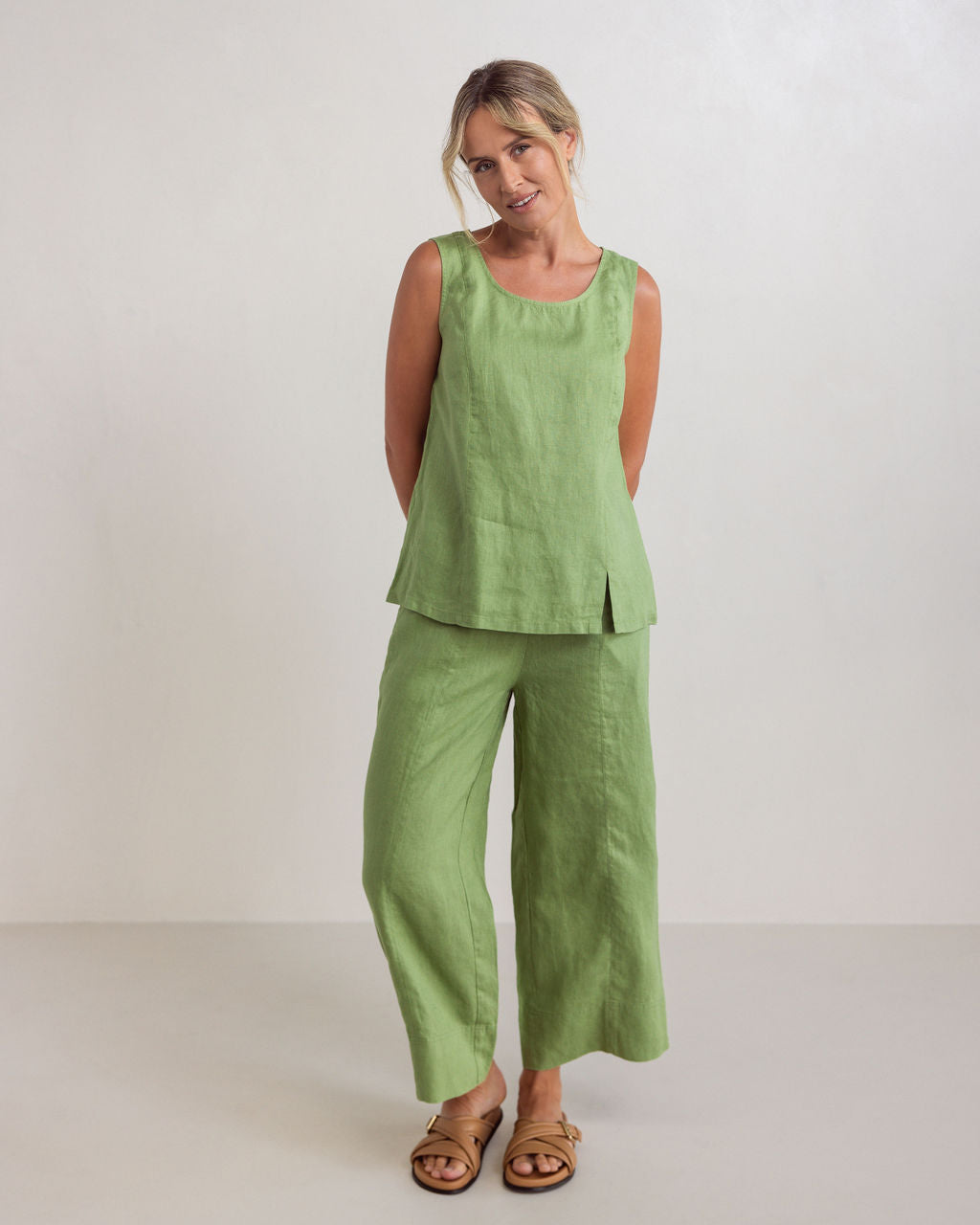 Woman wearing See Saw linen wide leg pants in pistachio with matching top with brown sandals against a white background