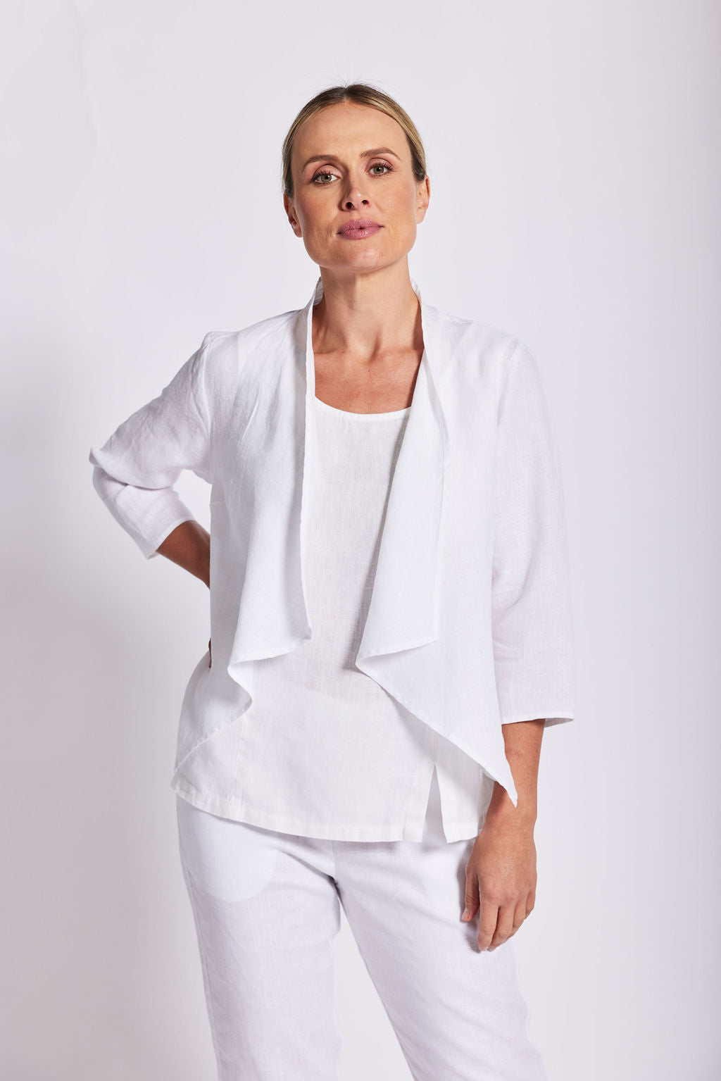 Woman modelling a white drape jacket by see saw in a studio.