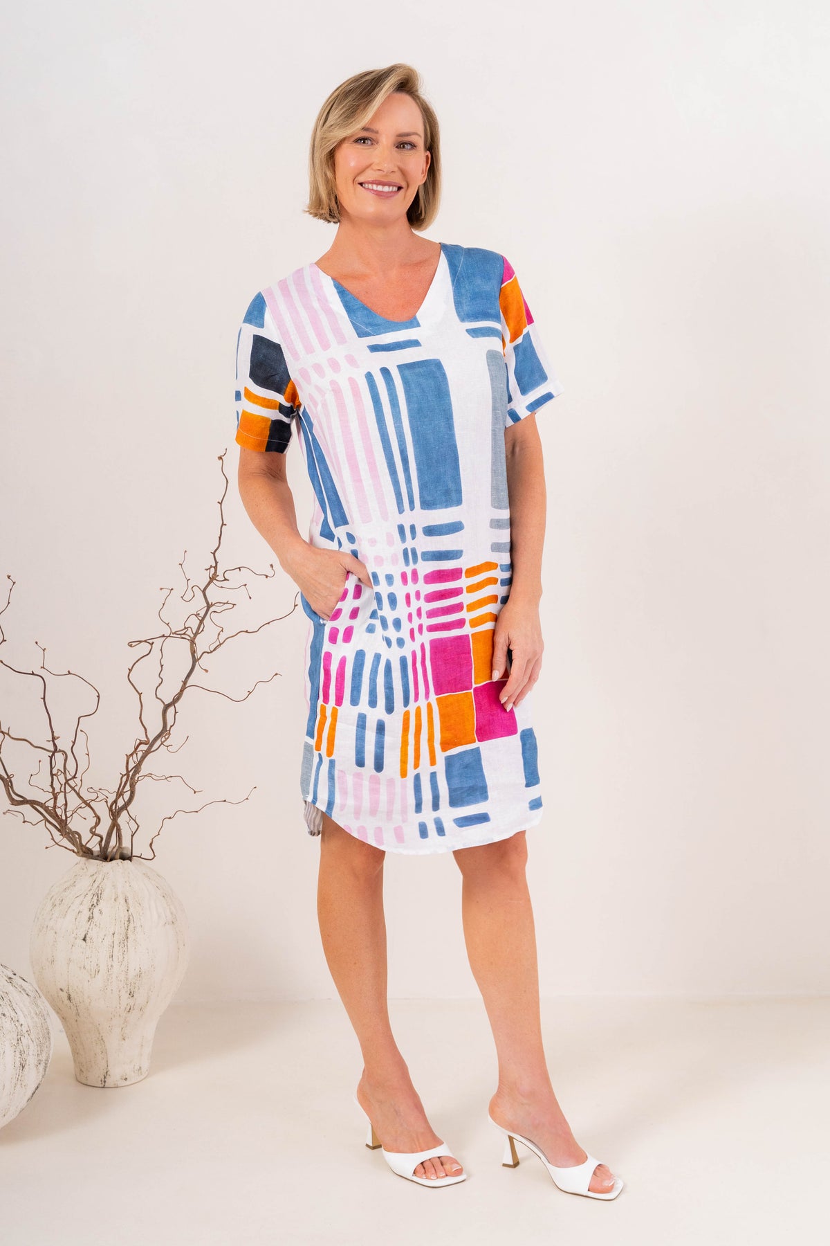 Woman modelling gallery print see linen dress in a neutral studio setting.