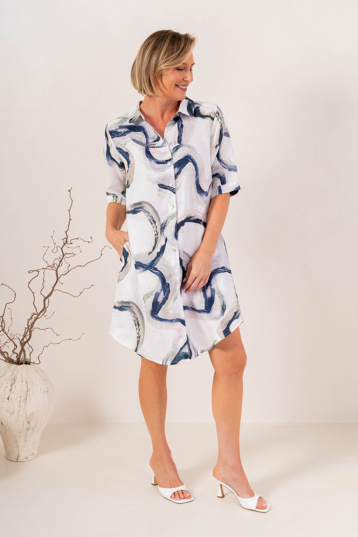 Woman modelling see saw linen shirtmaker style dress in riverstone print in studio setting.