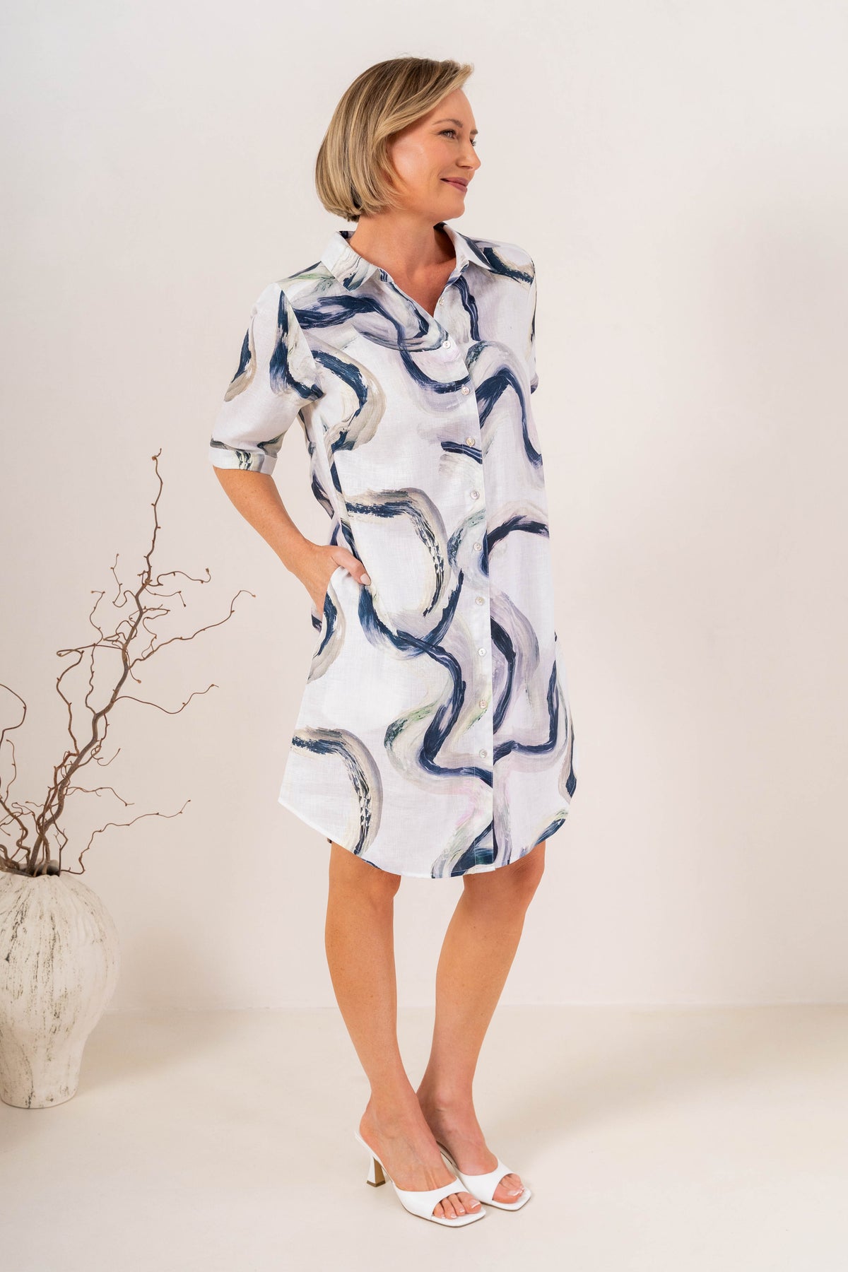 Woman modelling see saw linen shirtmaker style dress in riverstone print in studio setting.