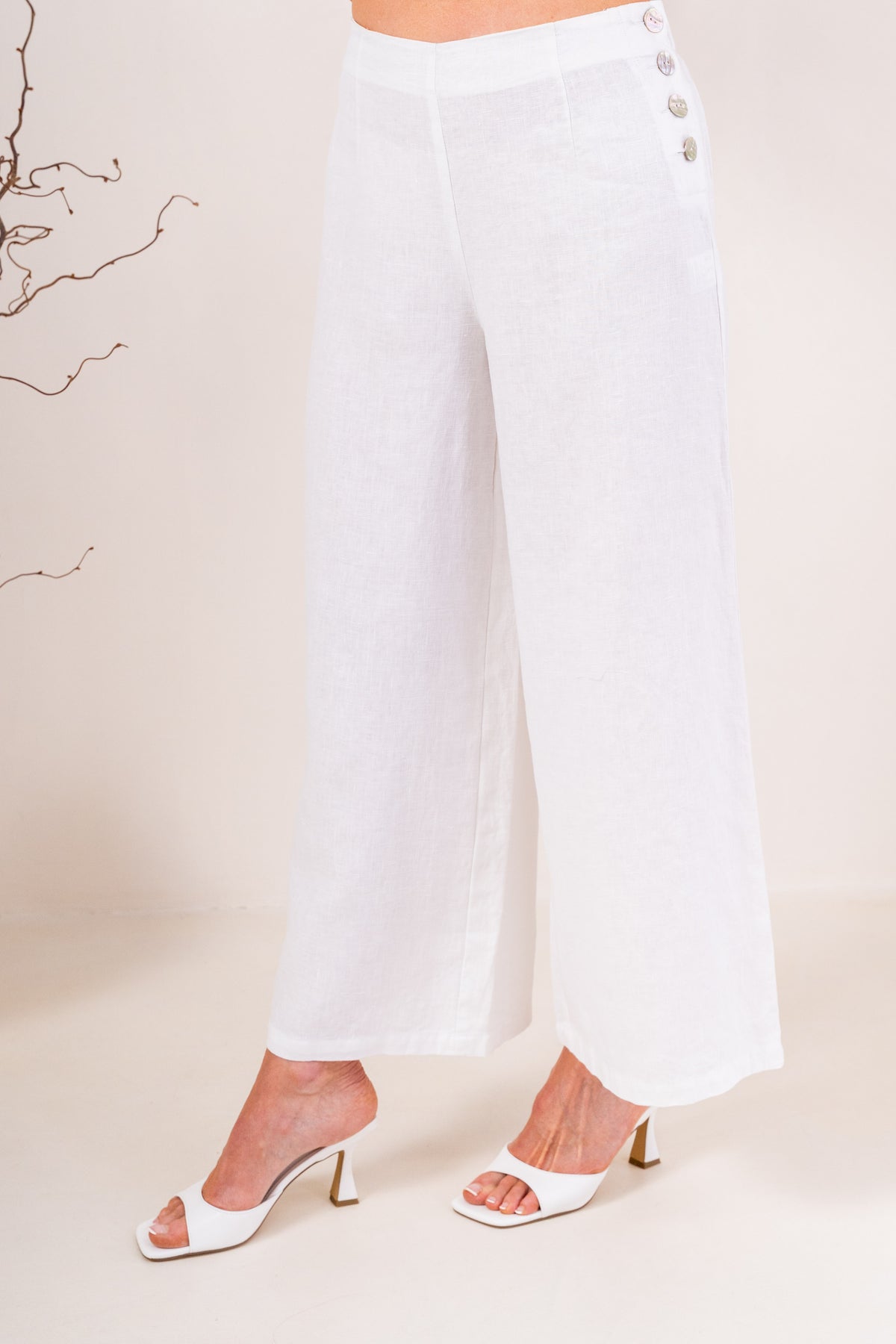 White wide-leg See Saw Palazzo linen pants shown on a model wearing white heeled sandals against a light beige background.