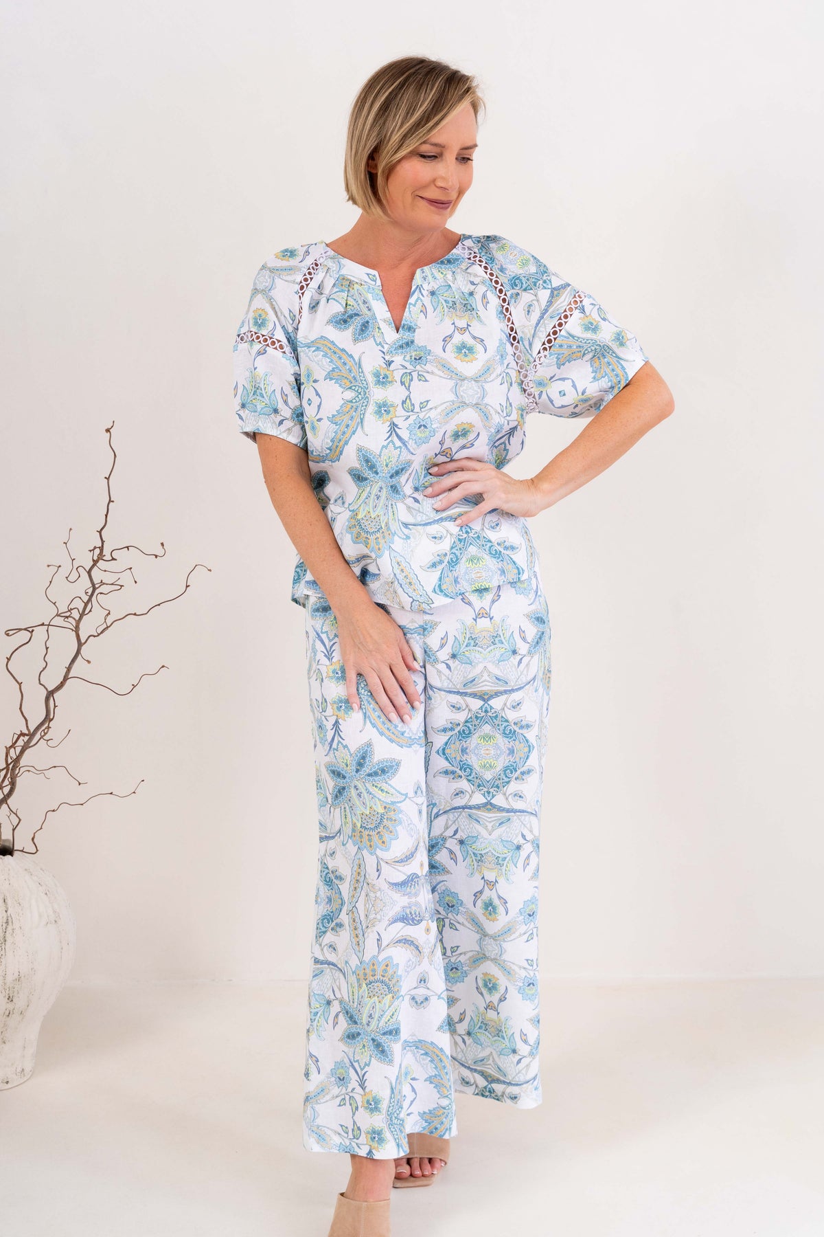 Woman modelling see saw linen top in botanica print with lace trim against a neutral background.