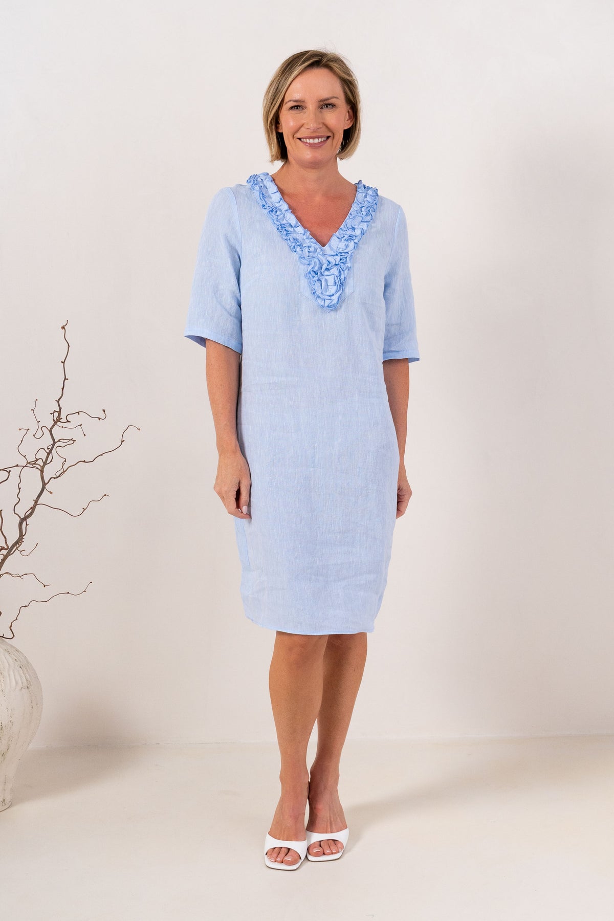 woman wearing linen see saw dress in white in architectural outdoor space.