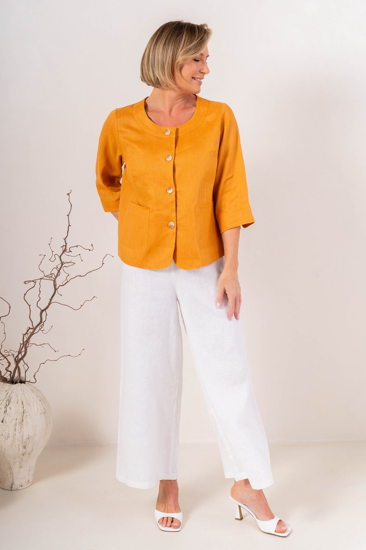 White wide-leg See Saw Palazzo linen pants shown on a model wearing white heeled sandals against a light beige background.