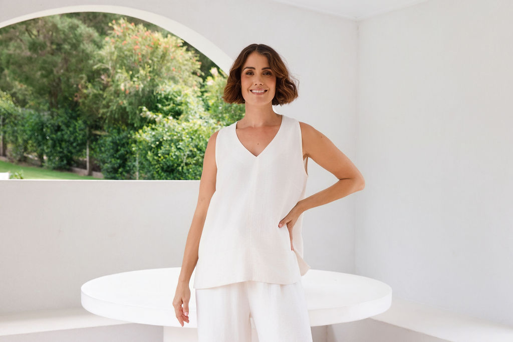 Model wearing See Saw Matching tank and pant in natural in linen and rayon blend. standing in an outdoor architecturally designed patio.