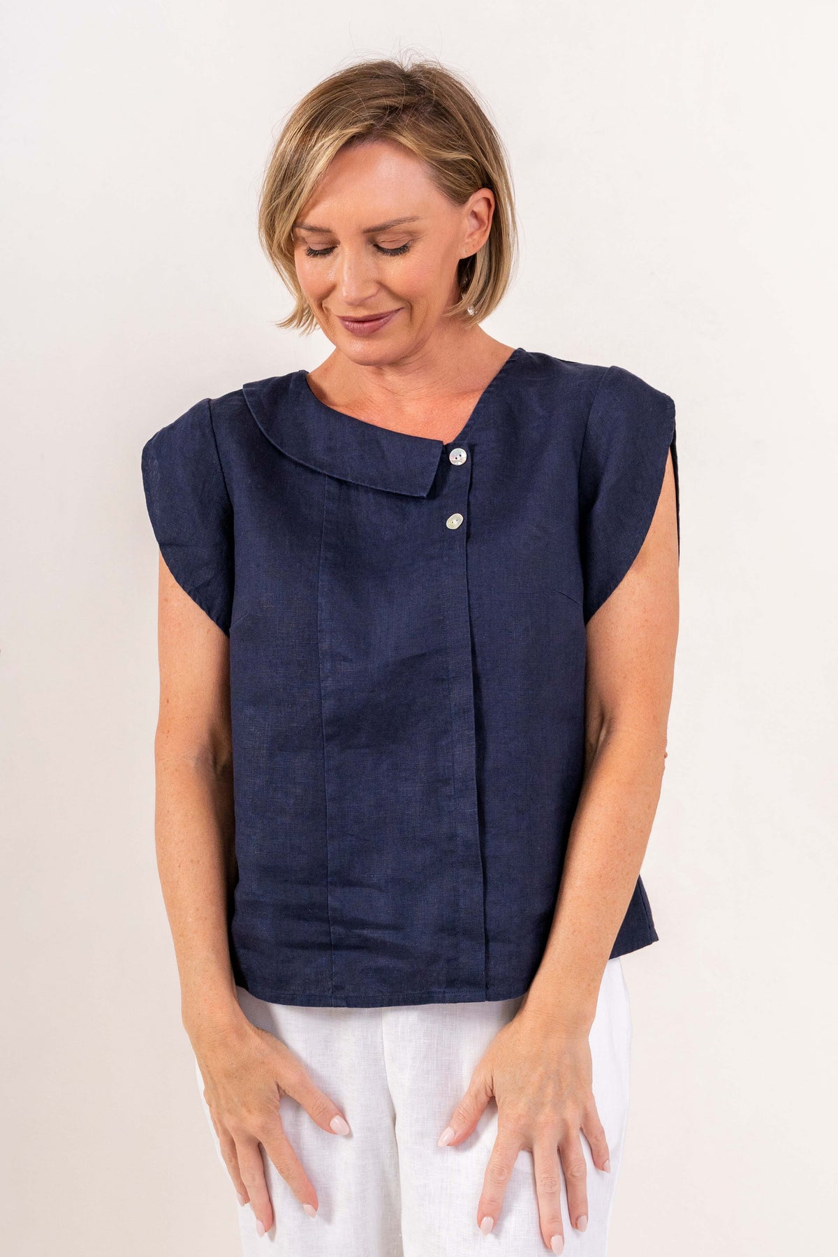 Model wearing see saw linen 2 button cowl neck top in navy.