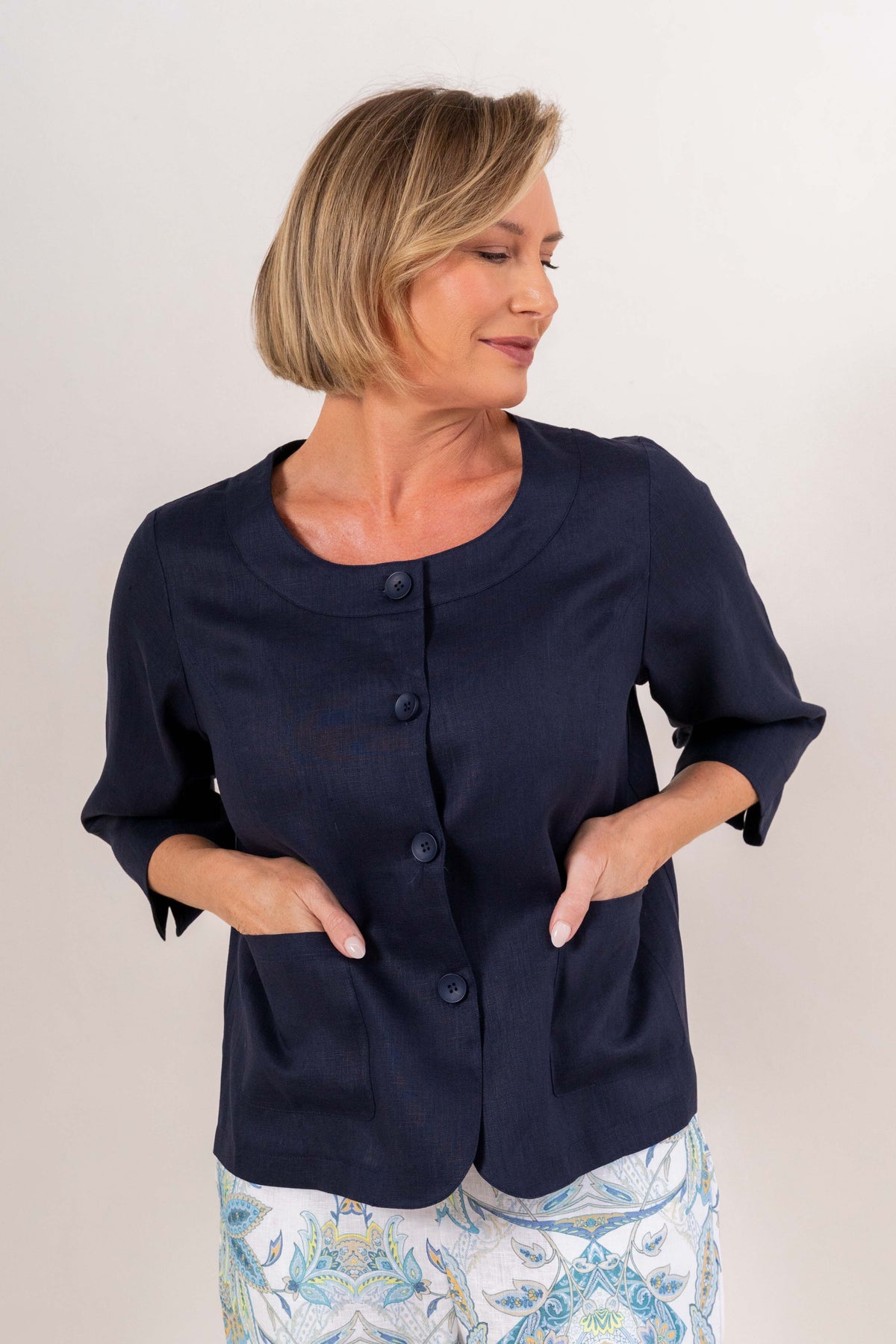 Woman modelling navy linen see saw utility jacket top and botanica 7/8 pants against a plain background.