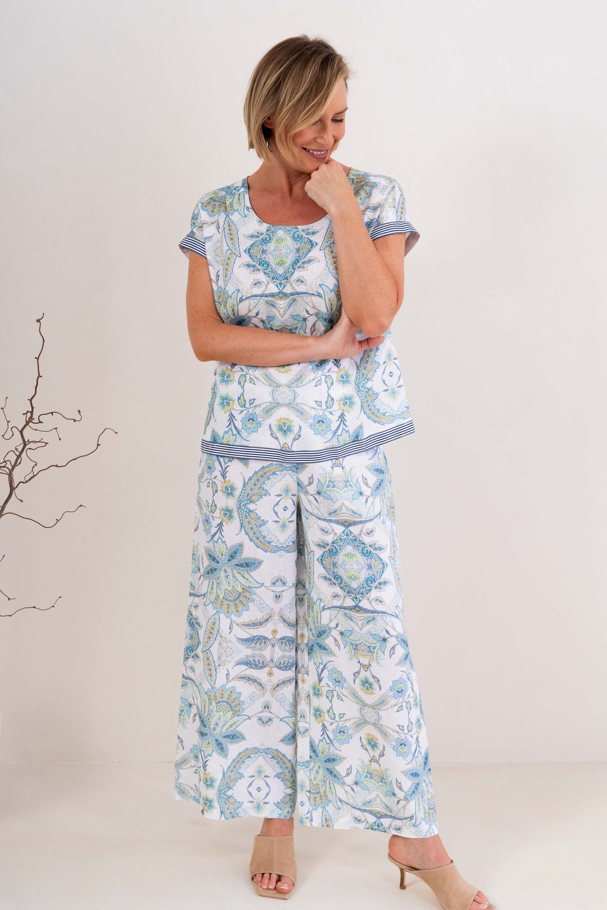Woman wearing pure linen botanica print cap sleeve top against a neutral background.