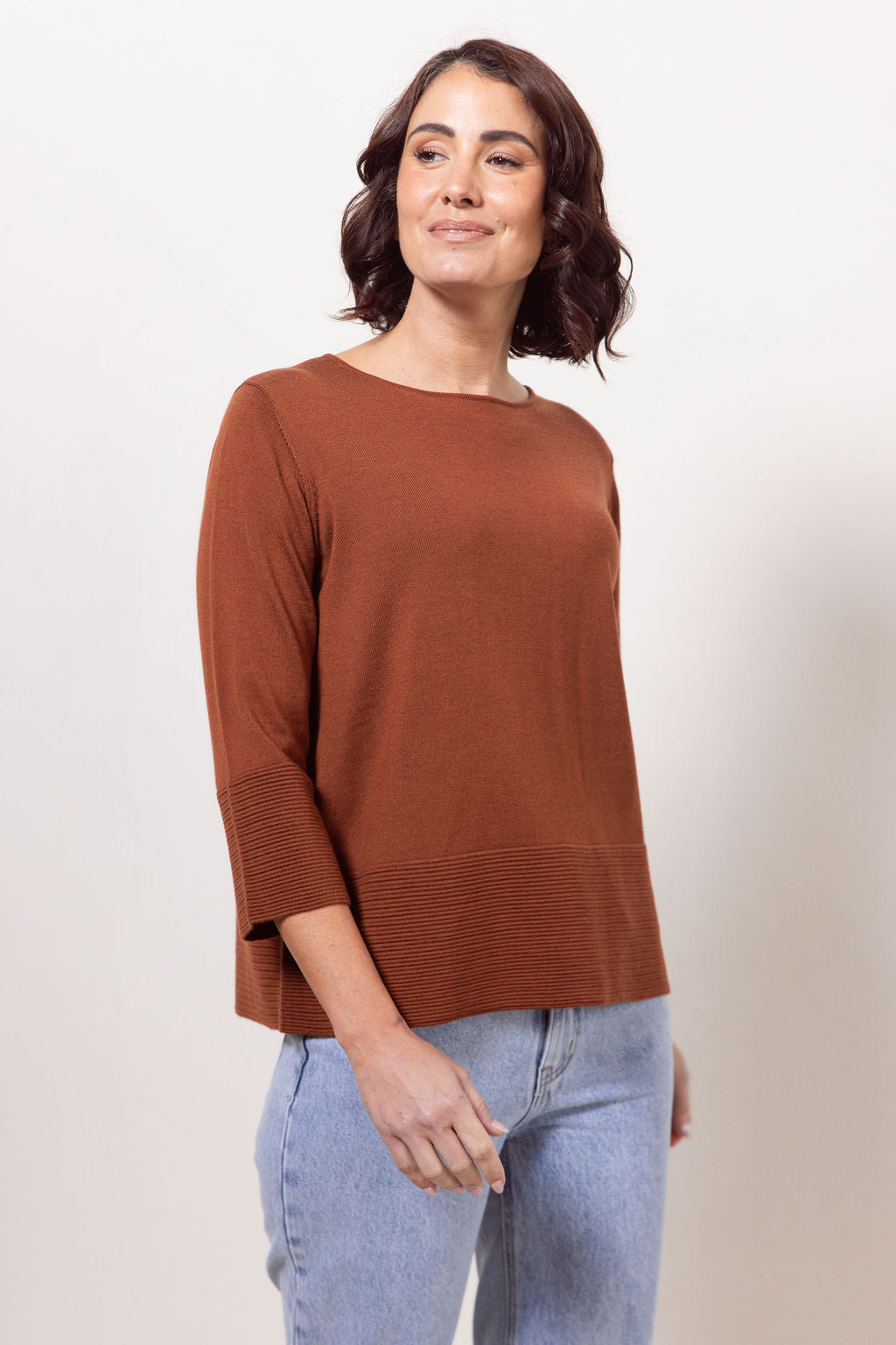 Woman wearing a copper See Saw Merino Wool sweater and patterned scarf against a white background