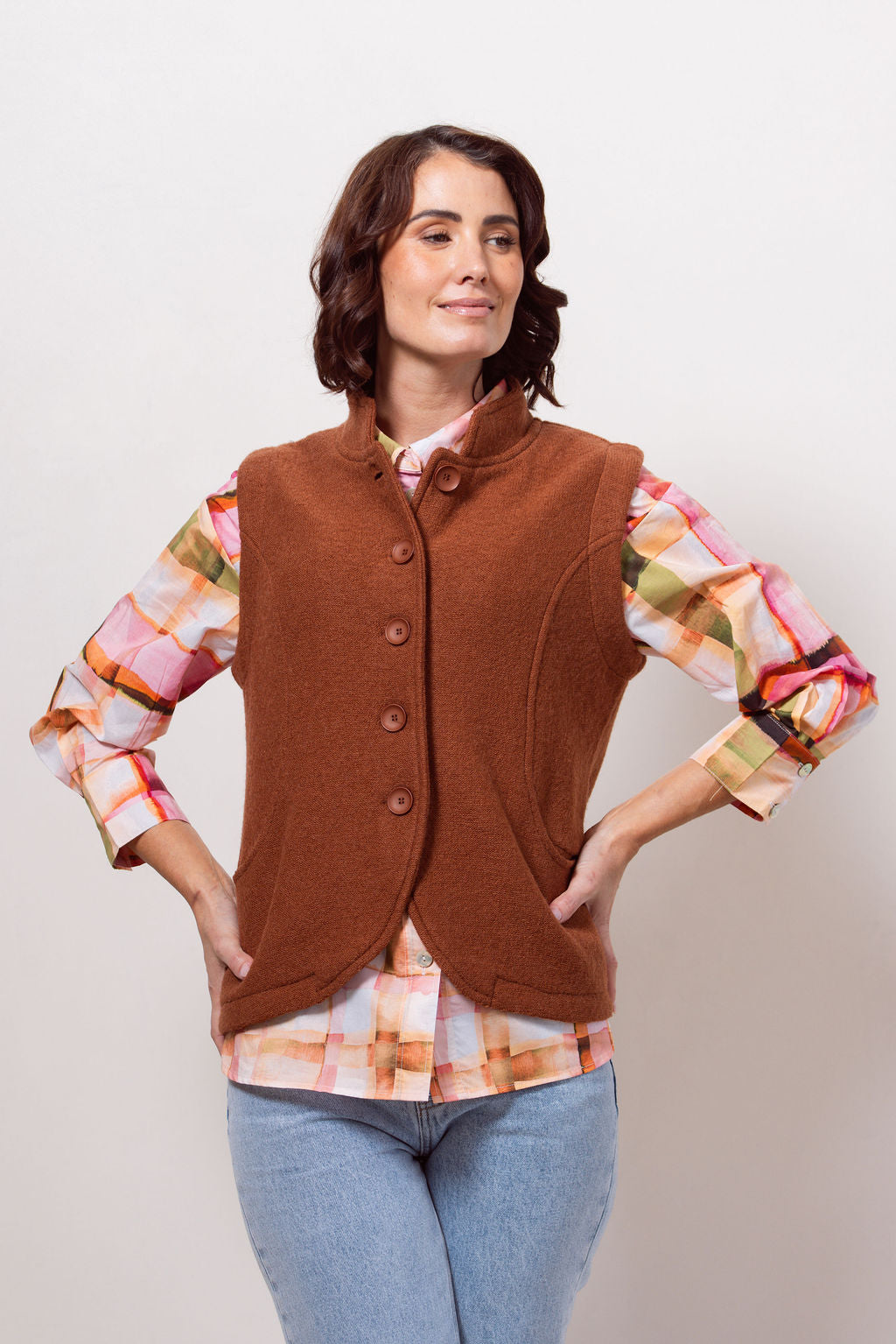 Woman wearing a copper See Saw vest over a plaid shirt with a plain background