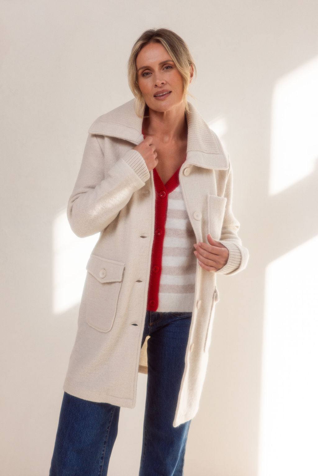 Woman wearing a beige See Saw boiled wool coat and sweater against a light background