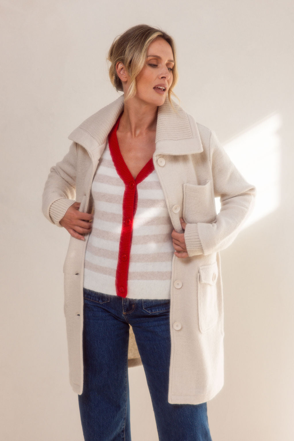 Woman wearing a beige See Saw boiled wool coat and sweater against a light background