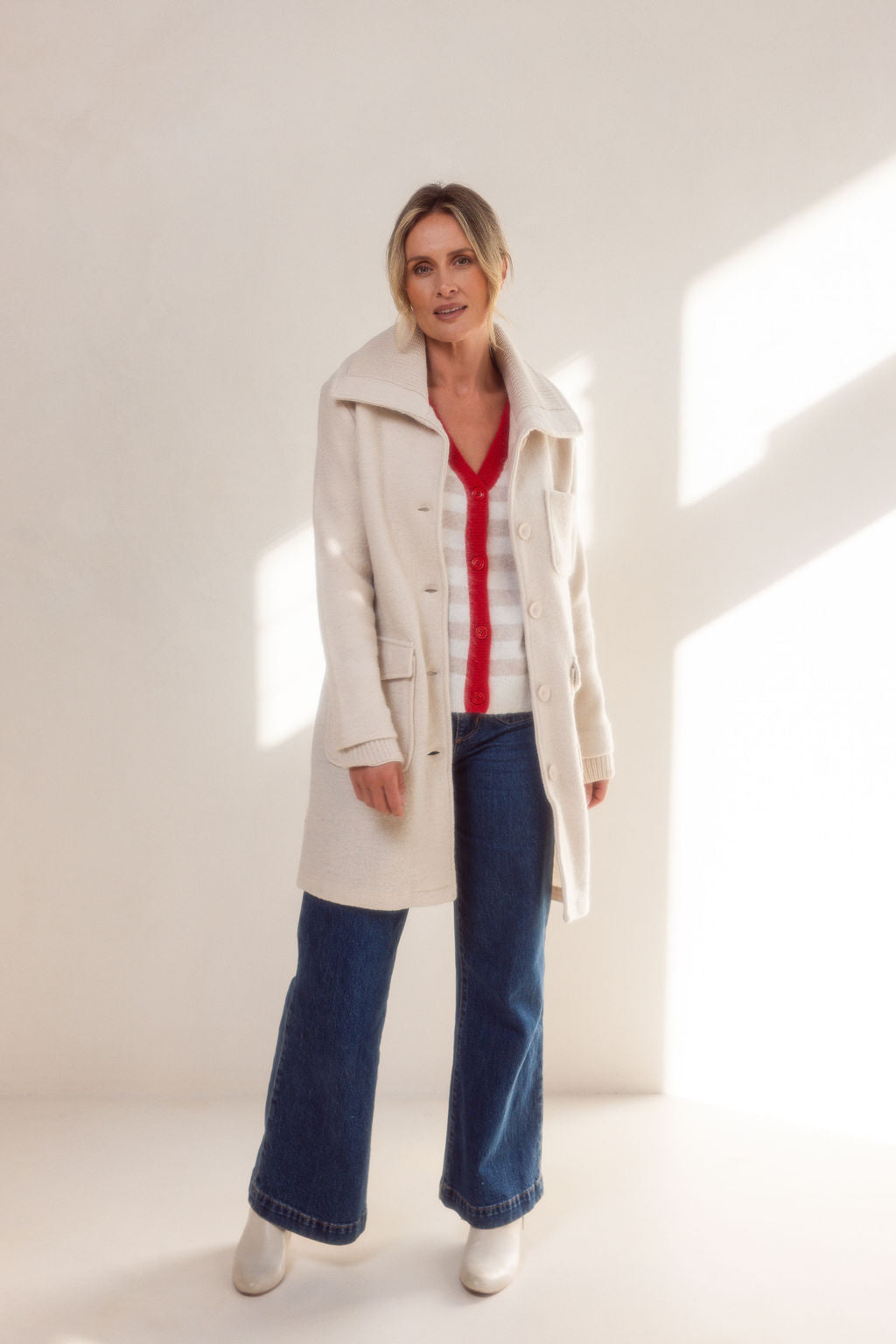 Woman wearing a beige See Saw boiled wool coat and sweater against a light background