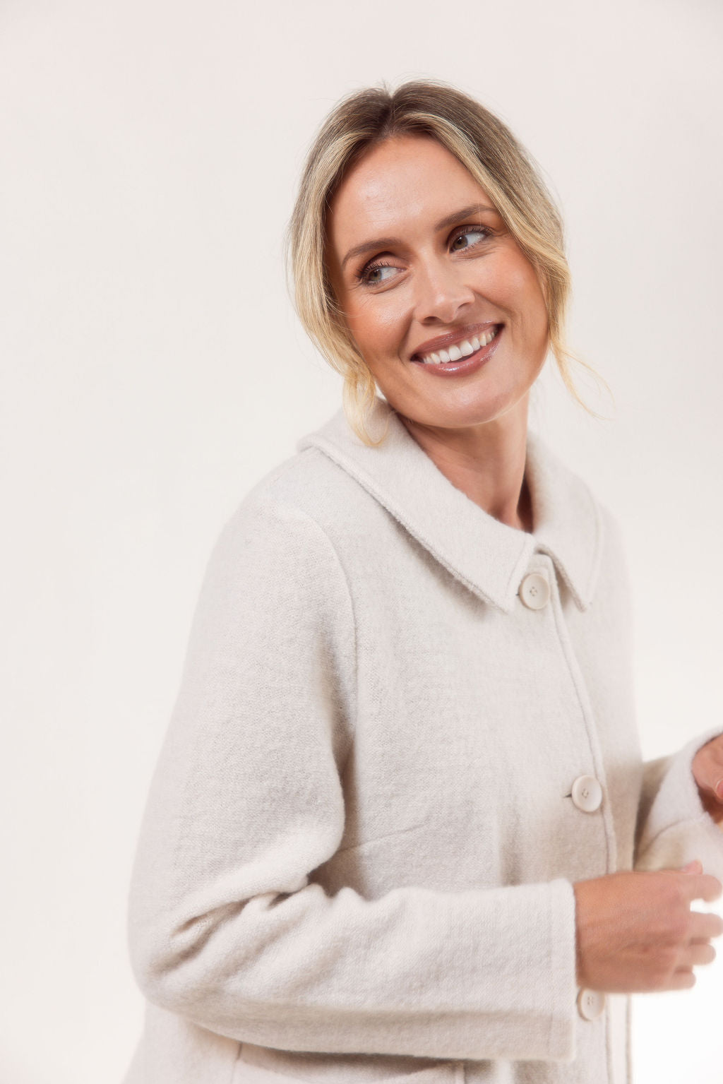 Woman wearing a cream See Saw boiled wool jacket and blue jeans on a white background
