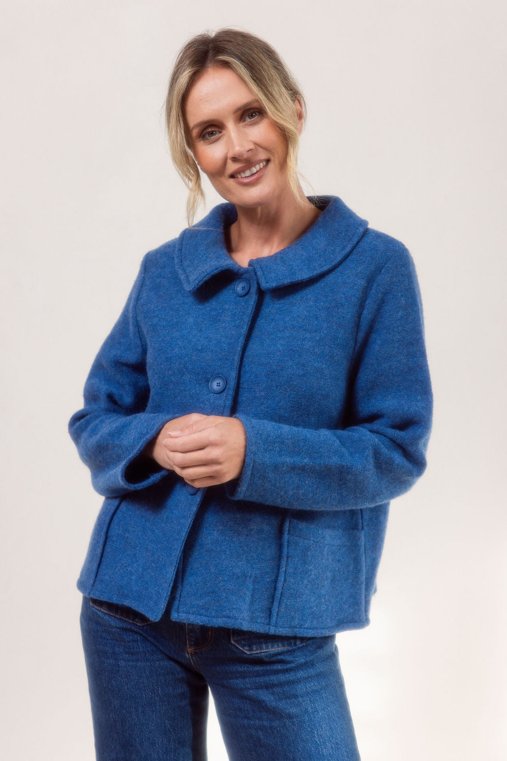 Woman wearing a denim See Saw boiled wool jacket and blue jeans on a white background