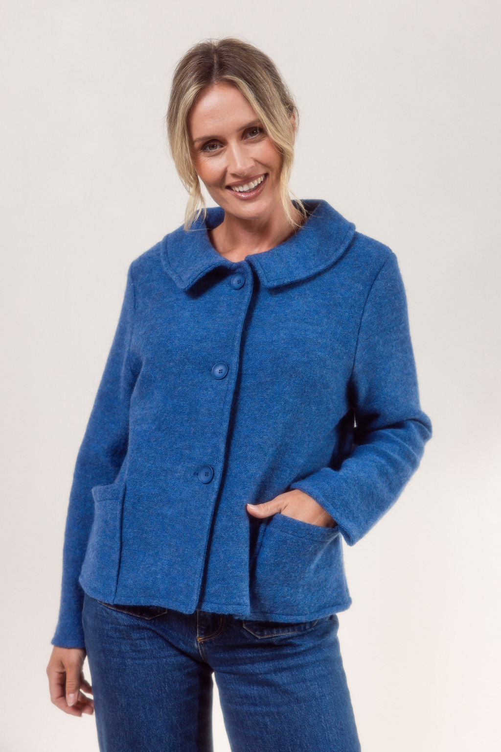 Woman wearing a denim See Saw boiled wool jacket and blue jeans on a white background