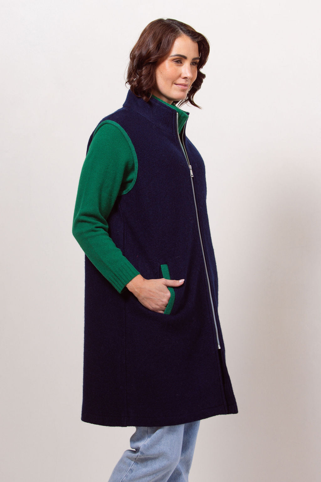 Woman wearing a navy See Saw boiled wool vest over a black long-sleeve shirt against a plain background