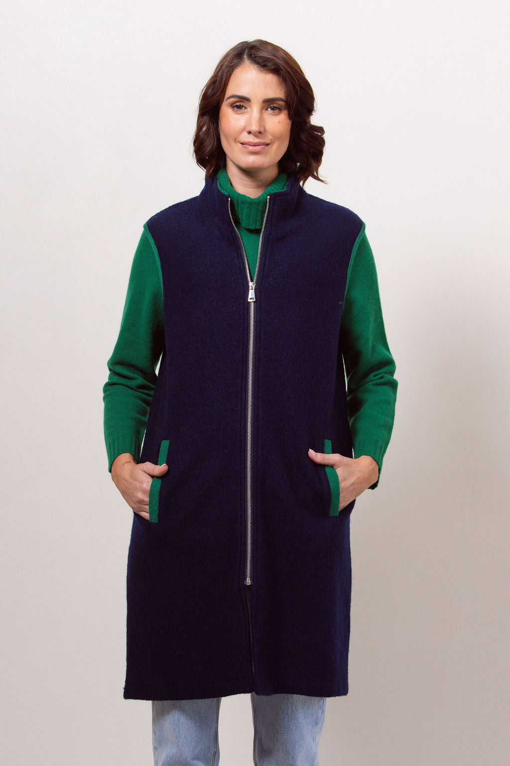 Woman wearing a navy See Saw boiled wool vest over a black long-sleeve shirt against a plain background