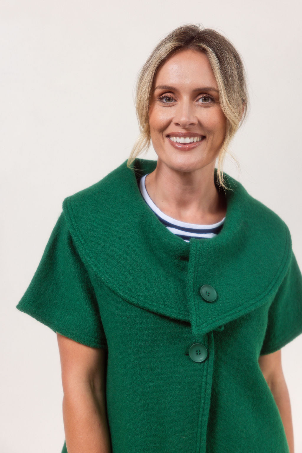Woman wearing a See Saw Boiled Wool green coat against a plain background.