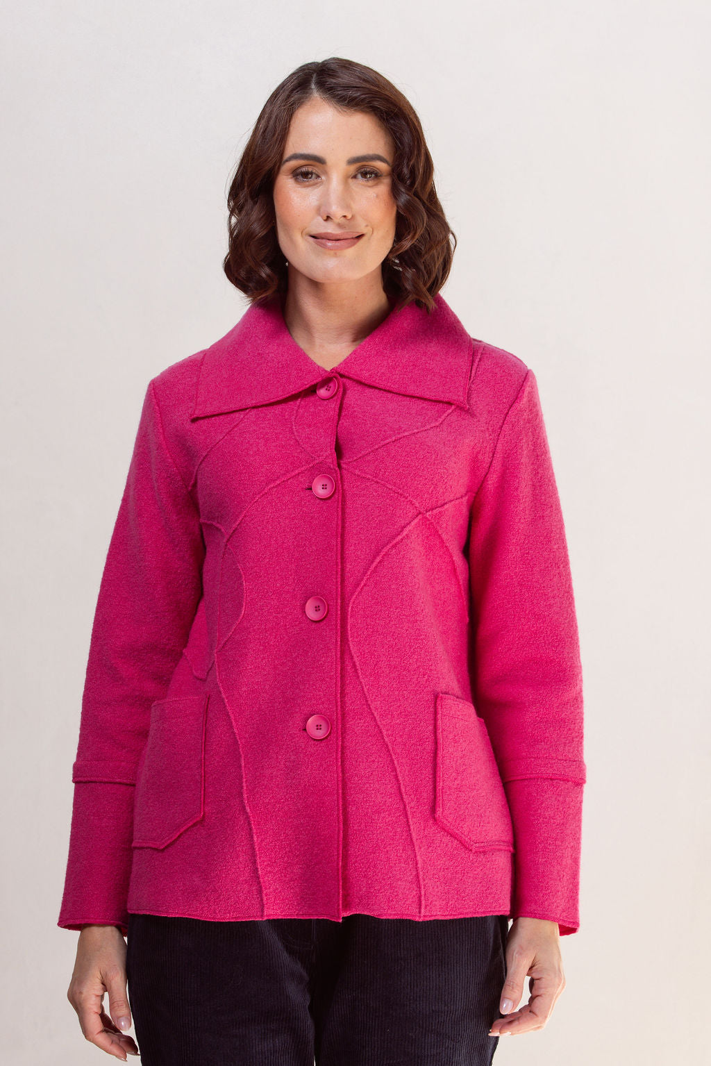 Woman wearing a bright pink See Saw Boiled wool coat against a plain background