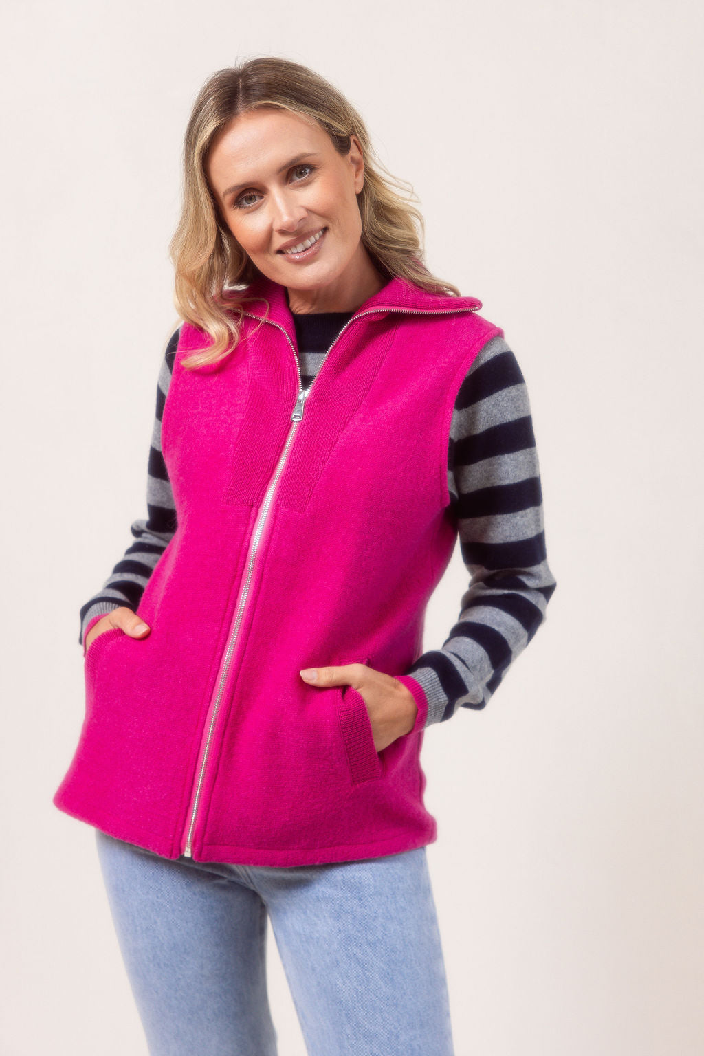 Woman wearing a See Saw pink zip-up vest over a white shirt with a plain background.