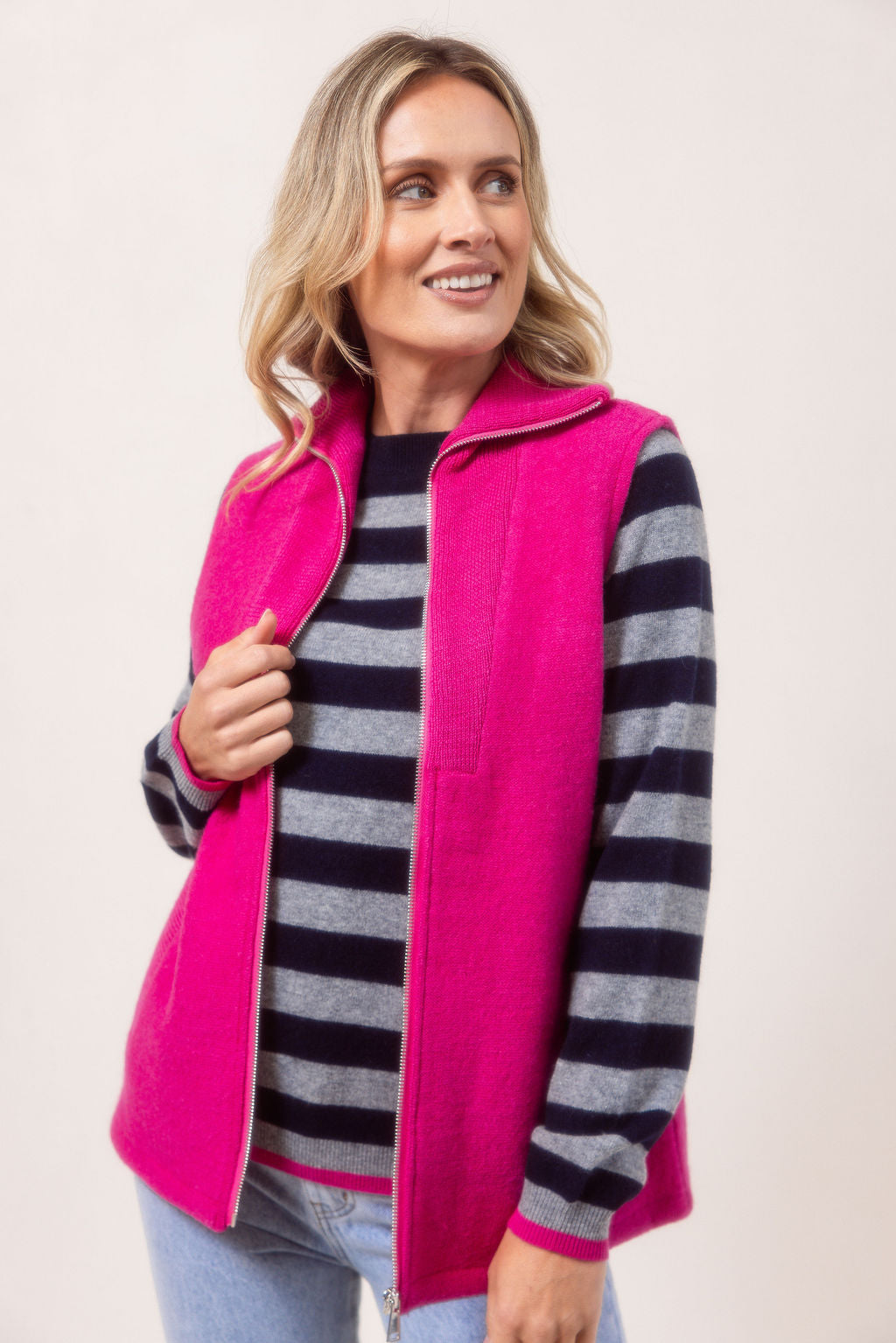Woman wearing a See Saw pink zip-up vest over a white shirt with a plain background