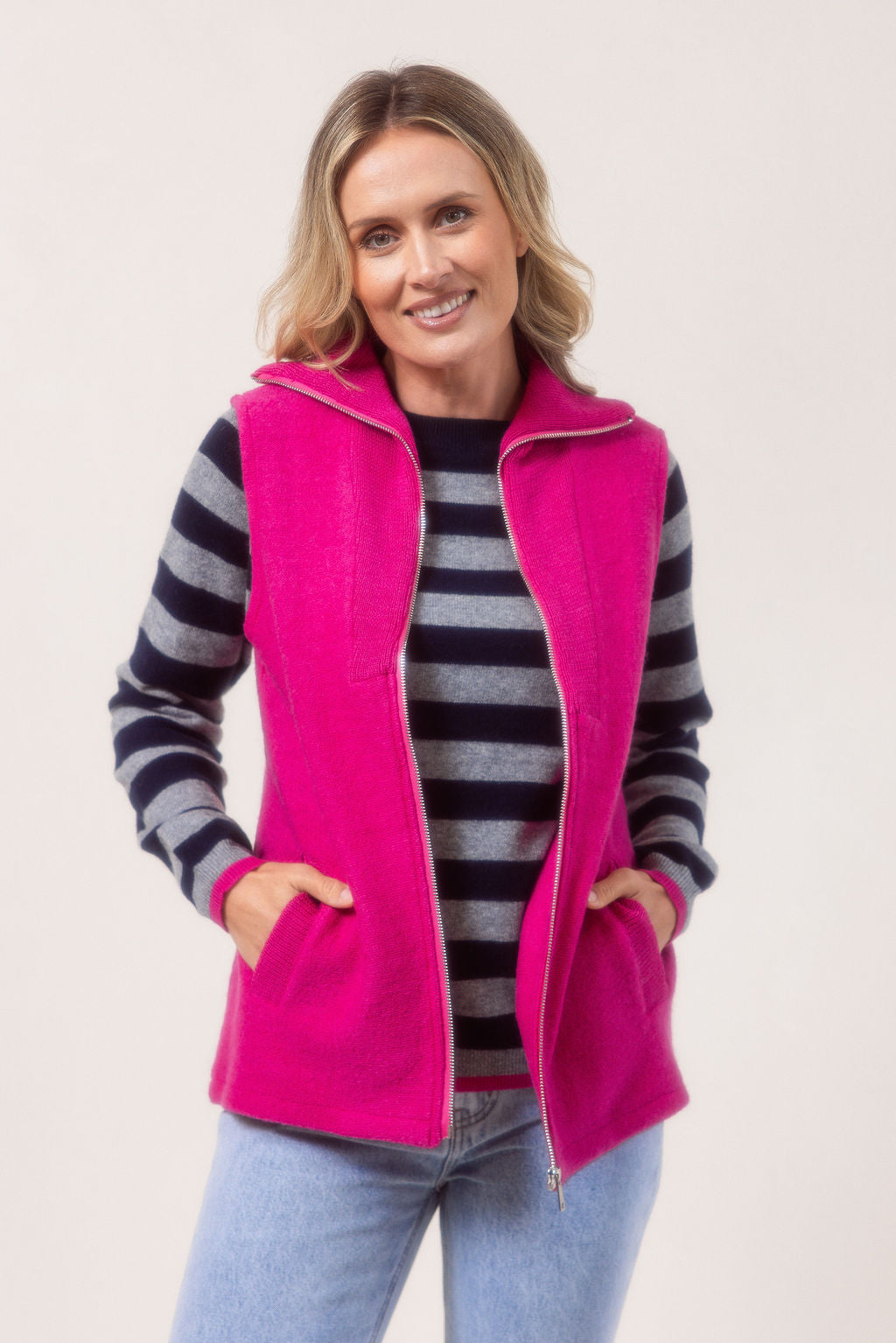 Woman wearing a See Saw pink zip-up vest over a white shirt with a plain background.