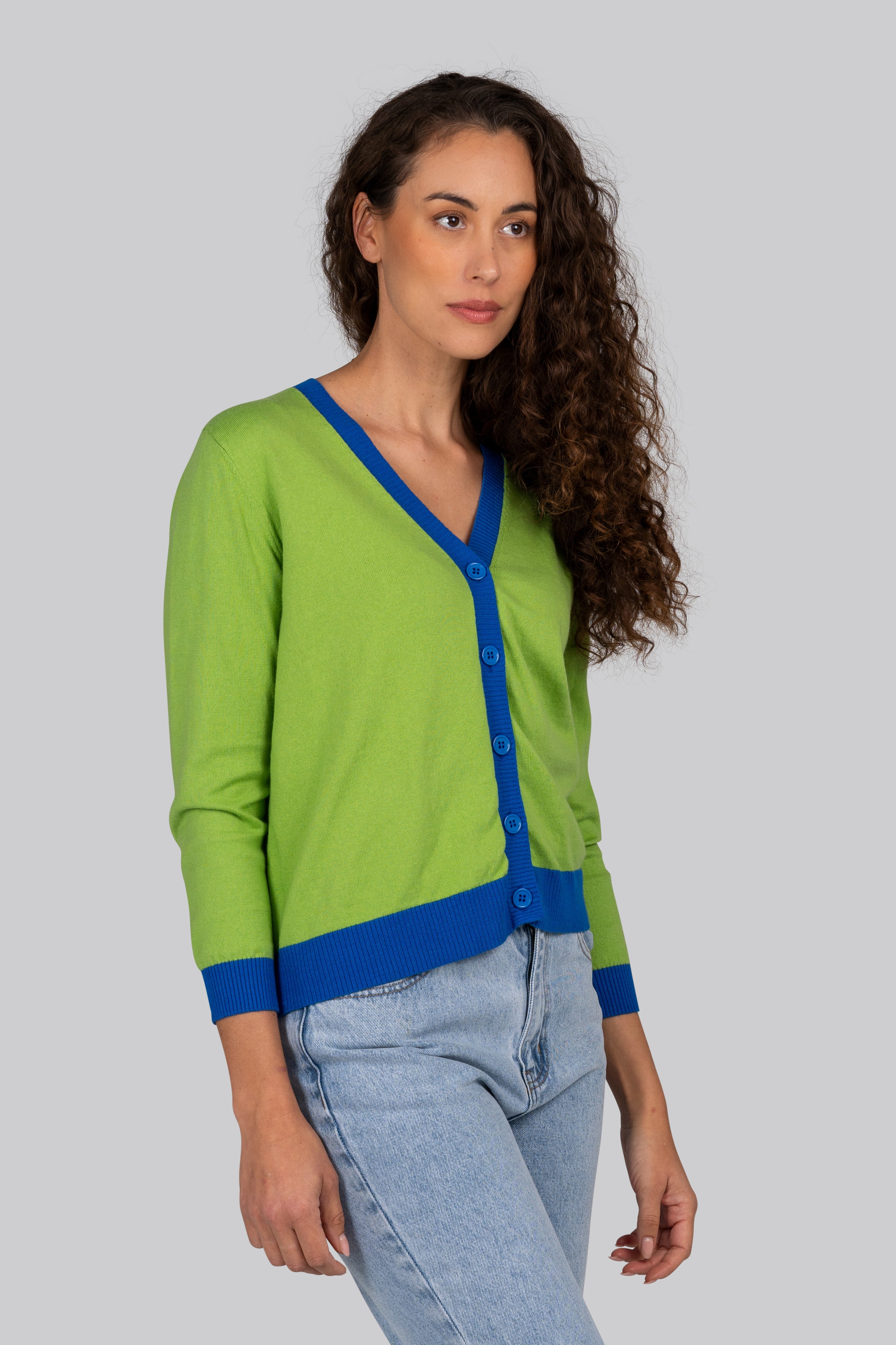 Woman wearing a green Kaleido cardigan with blue trim against a plain background