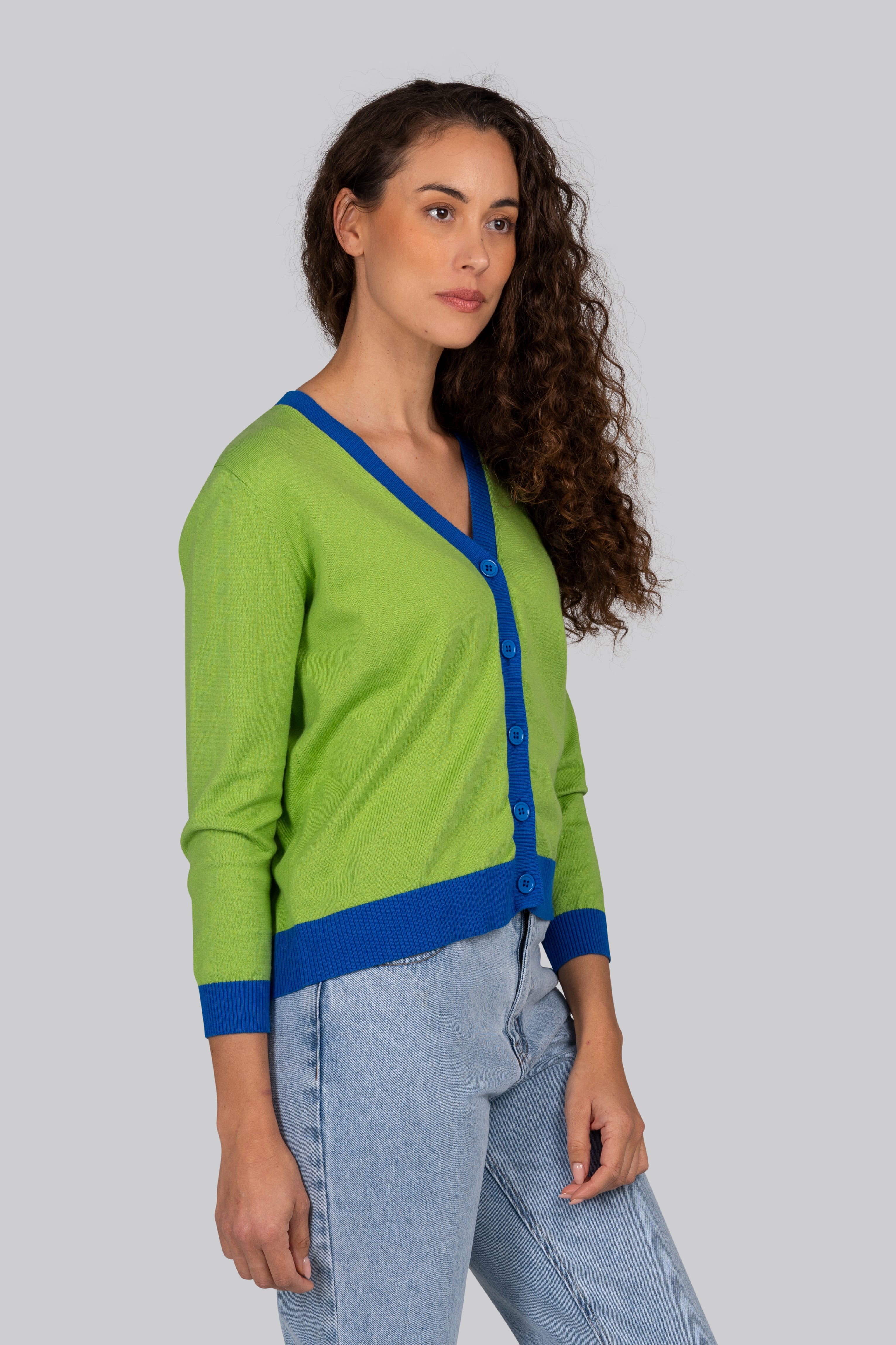 Woman wearing a green Kaleido cardigan with blue trim against a plain background