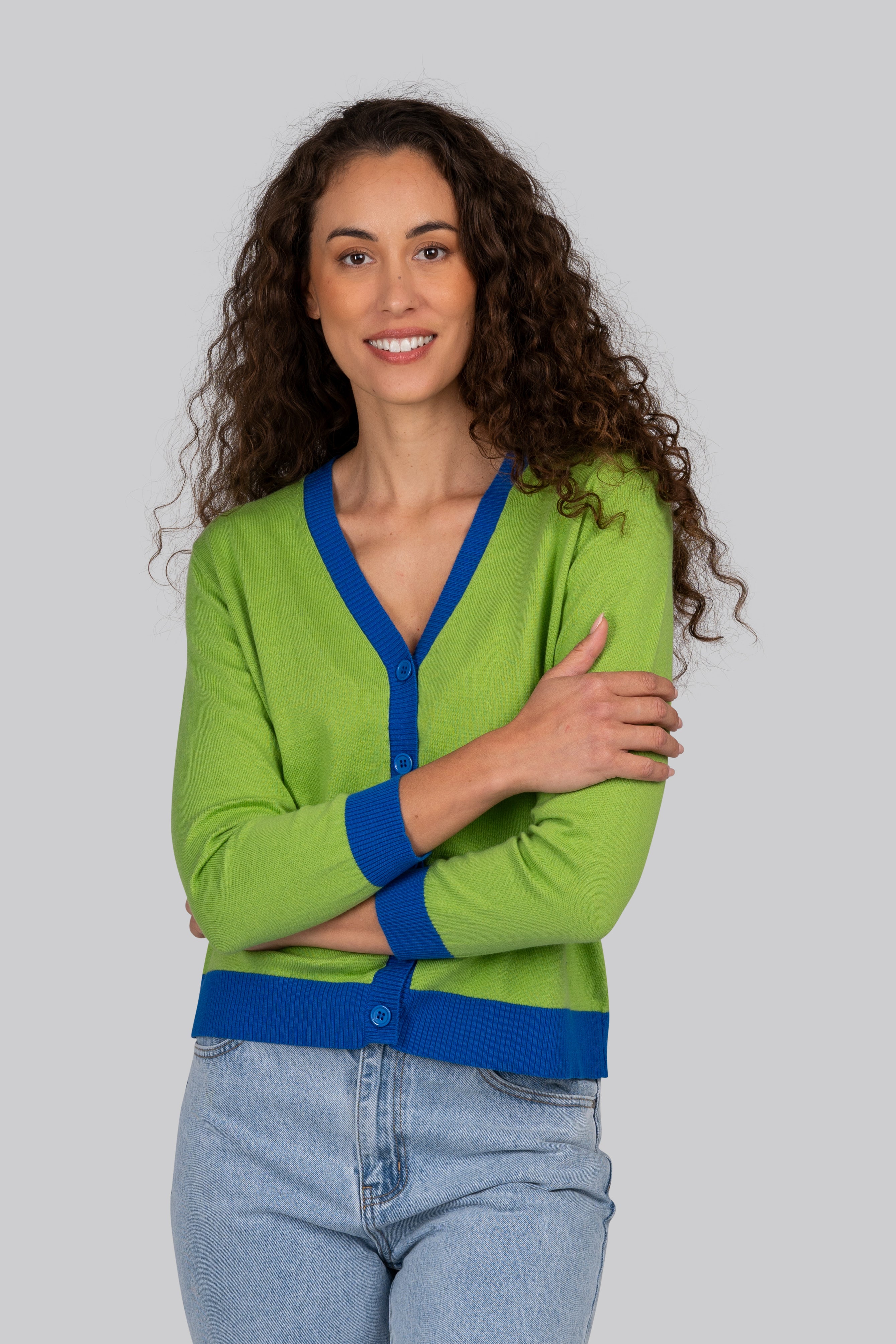 Woman wearing a green Kaleido cardigan with blue trim against a plain background