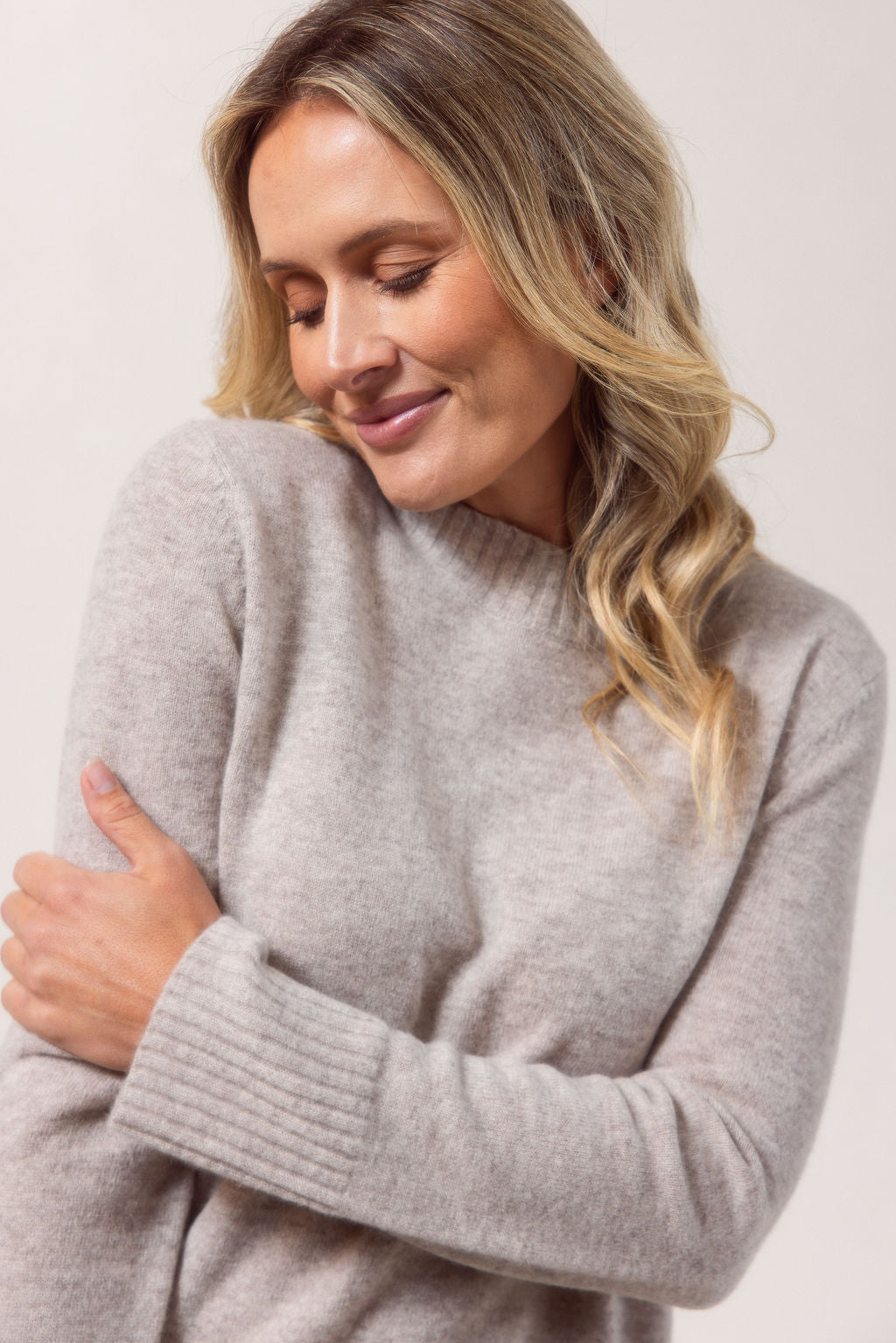 Woman wearing a Merino Wool See Saw sweater in wheat with Black accents on a plain background