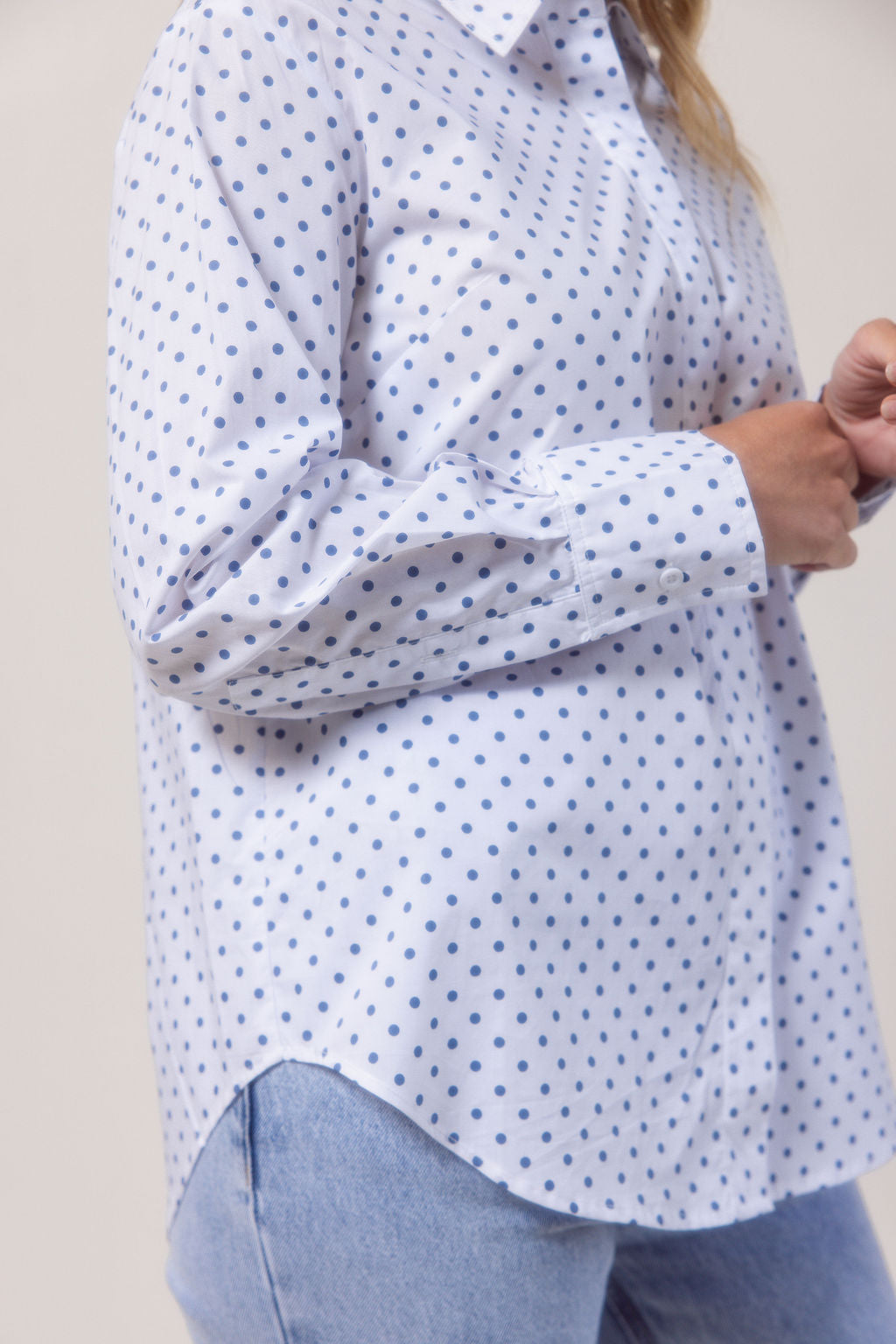 Woman wearing a classic white See Saw shirt with spot detail in a bright room with a vase and plant in the background