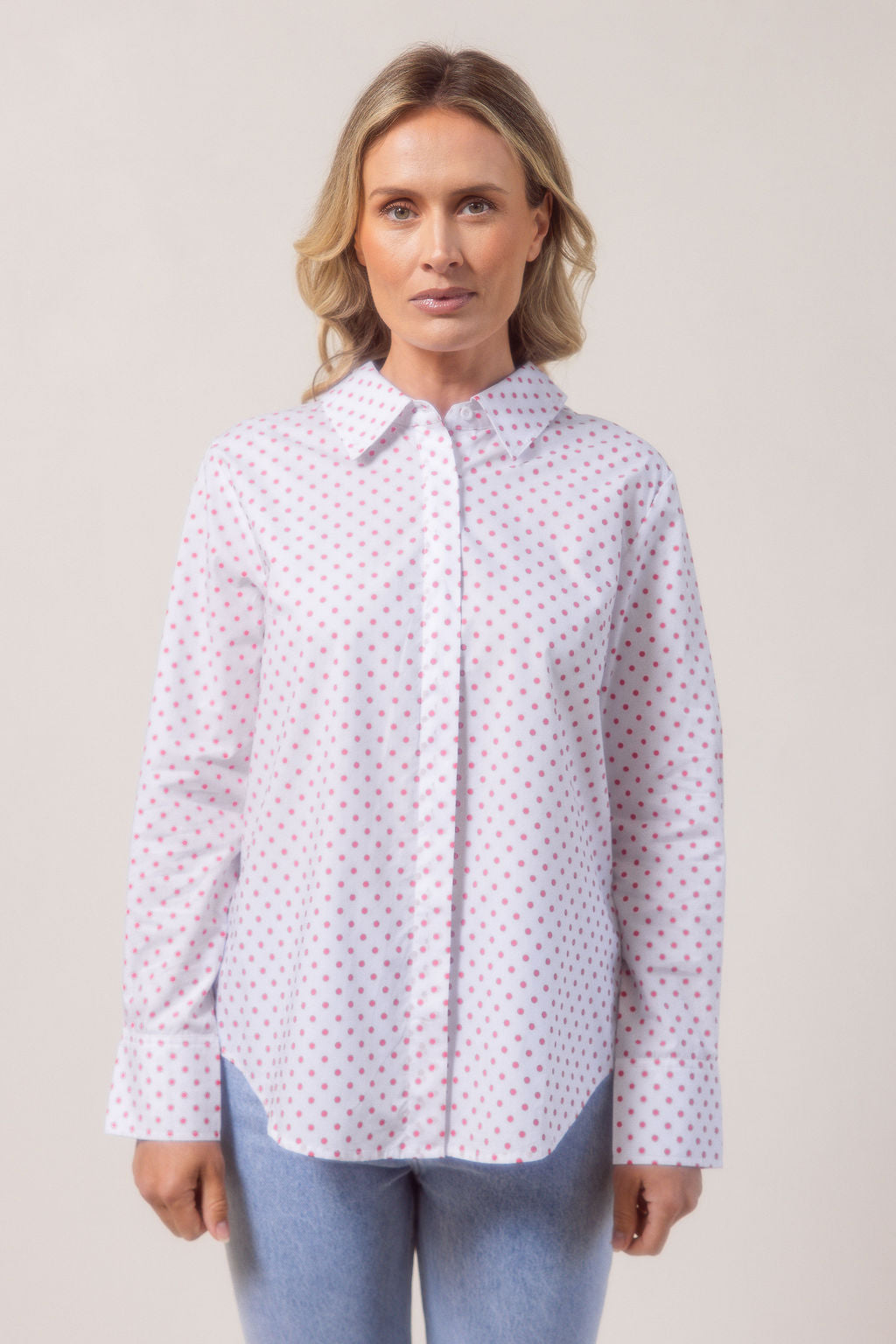 Woman wearing a classic white See Saw shirt with spot detail in a bright room with a vase and plant in the background