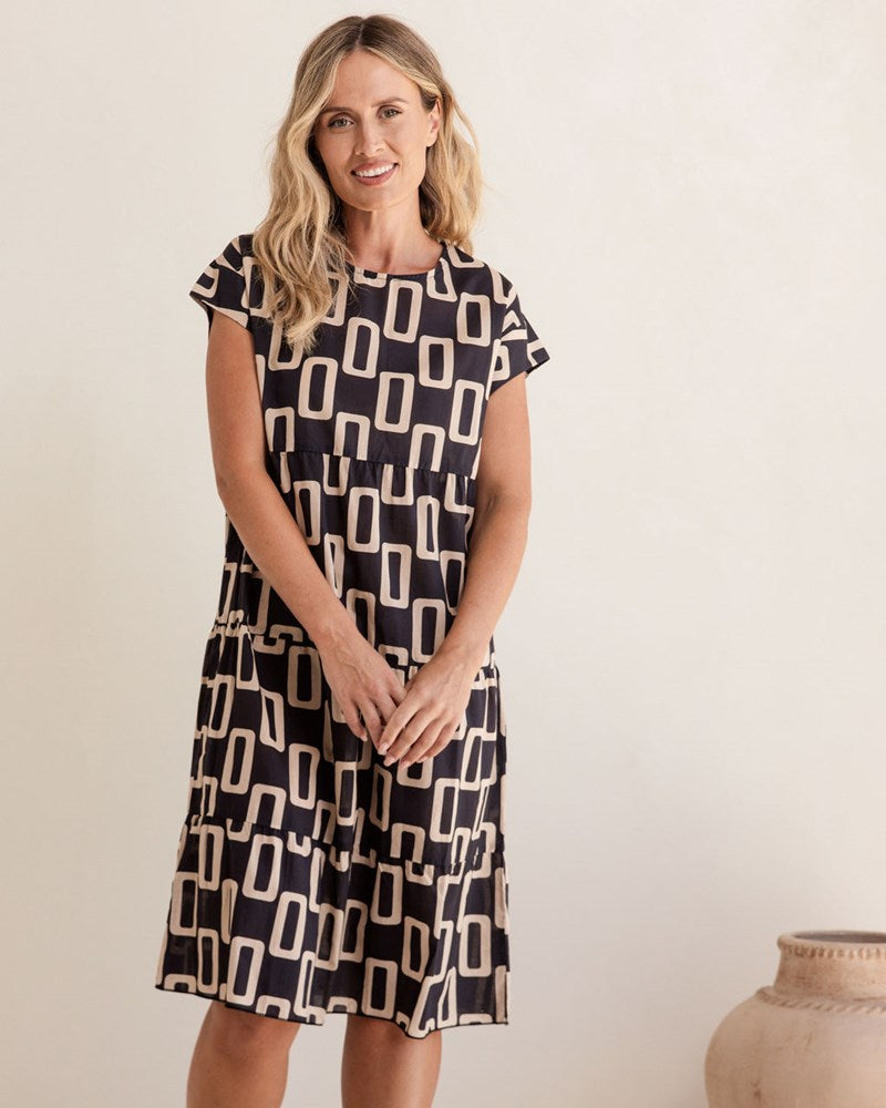 Woman wearing a black and white patterned dress against a plain background. See Saw Cotton Tiered Dress