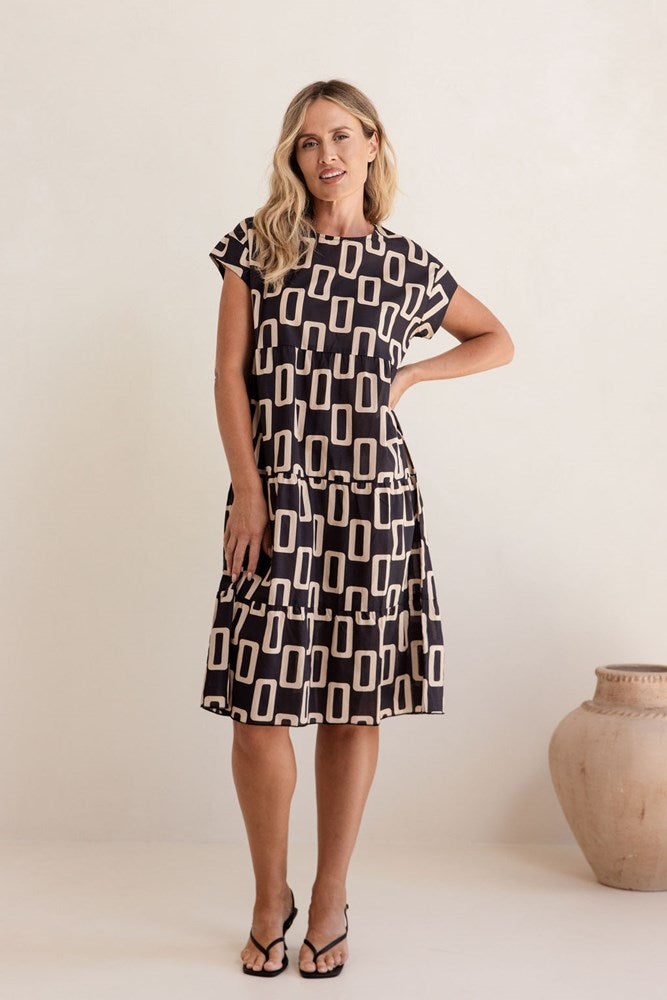 Woman wearing a black and white patterned dress against a plain background. See Saw Cotton Tiered Dress