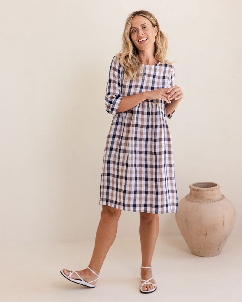 Woman wearing a blue and white checkered dress standing next to a decorative vase against a plain background. See Saw Linen Elbow Sleeve Button Back Dress
