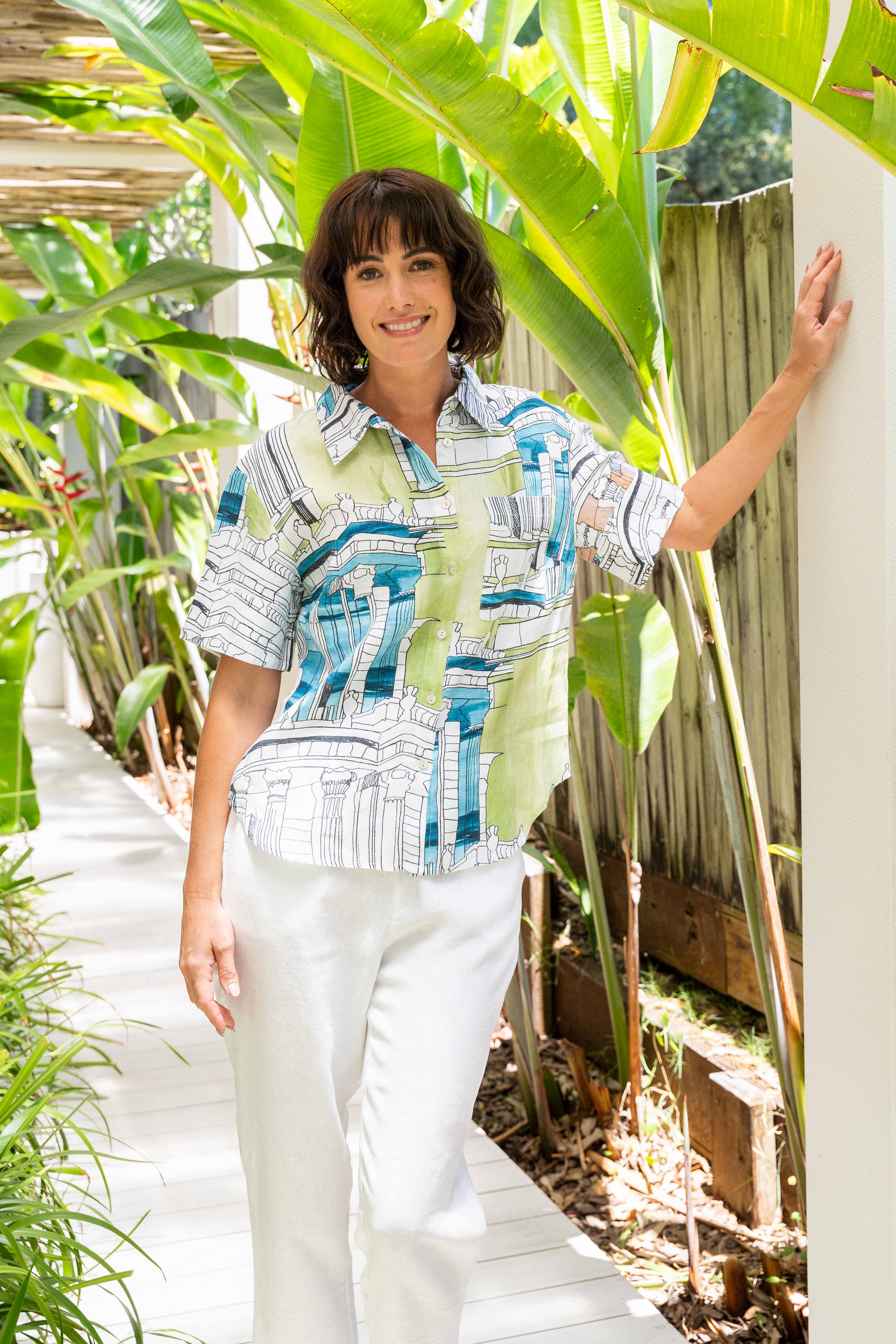 Woman standing outdoors with greenery around her. See Saw Linen Short Sleeve Shirt