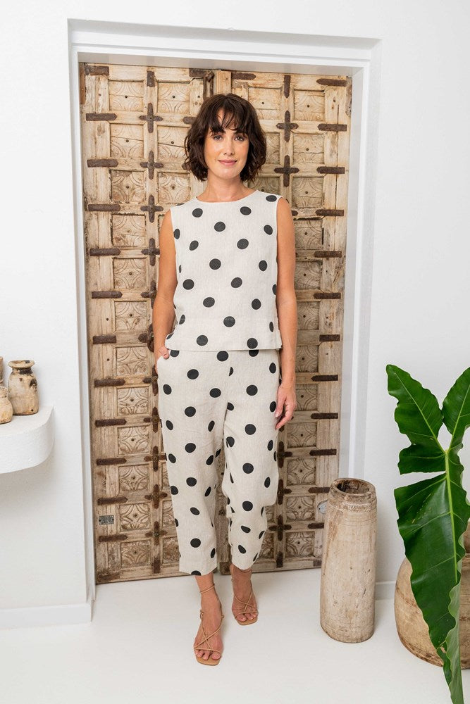 Woman wearing a polka dot outfit standing in front of a decorative wooden door. See Saw Linen Spot Pull on Pant