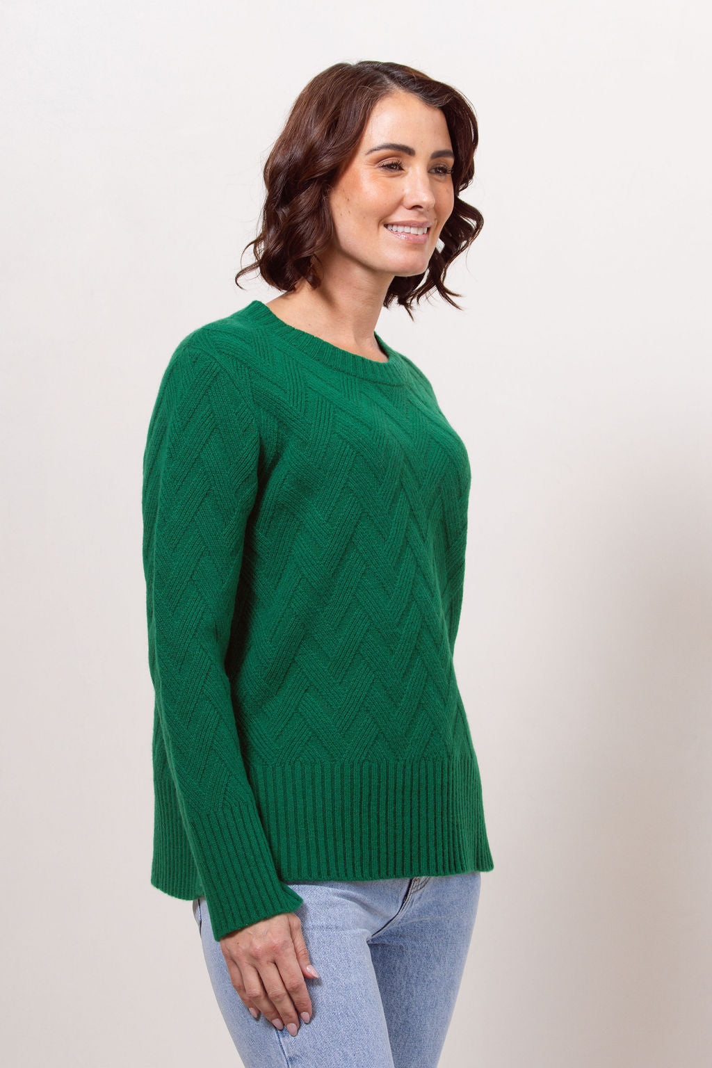 Woman wearing a green See Saw sweater against a plain background