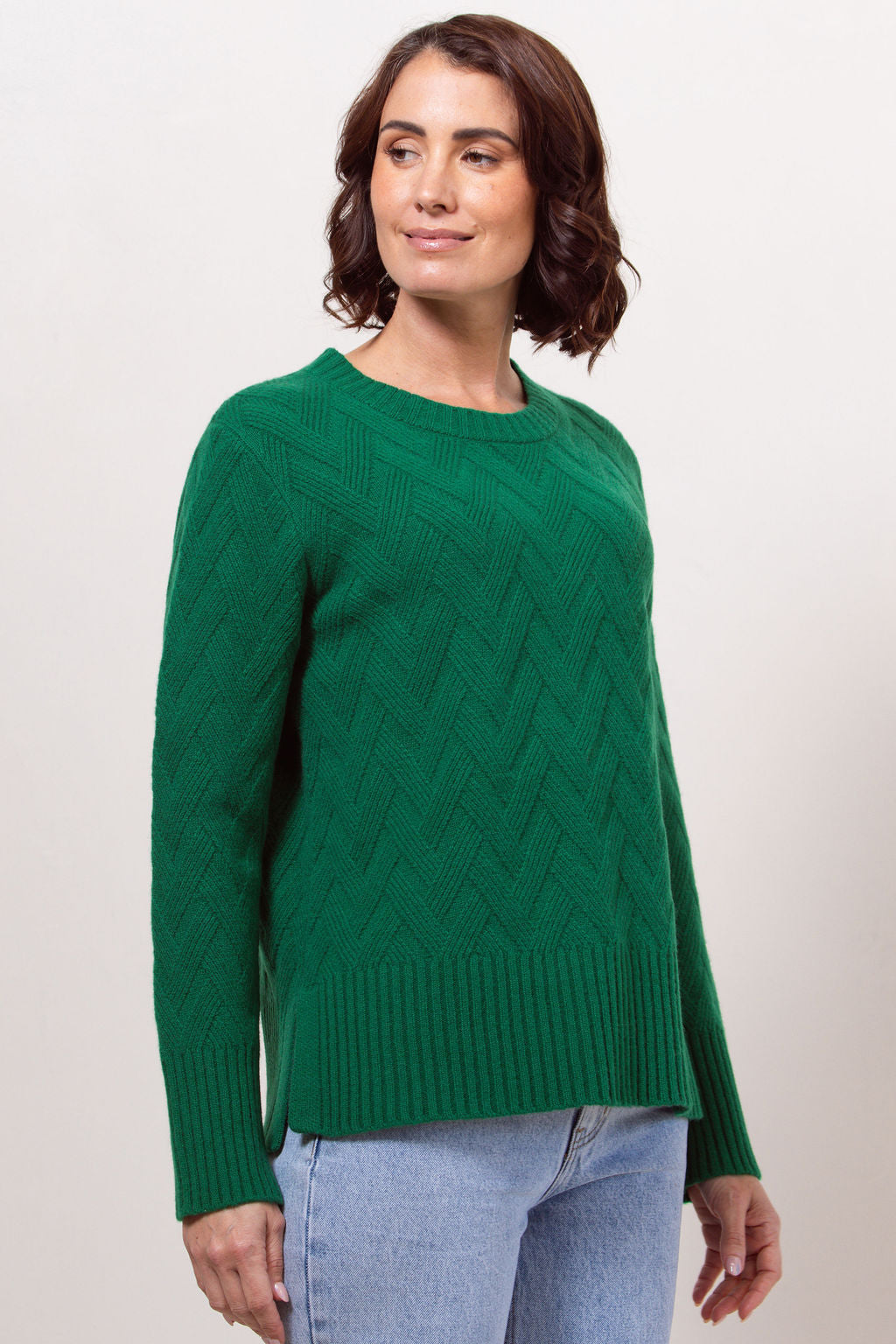Woman wearing a green See Saw sweater against a plain background