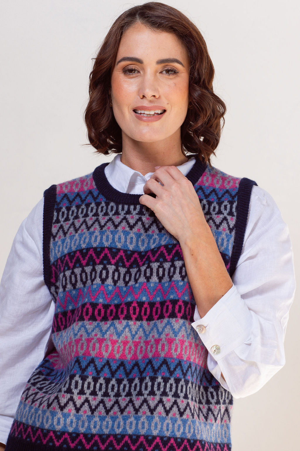 Woman wearing a See Saw jacquard patterned sweater vest over a white shirt on a plain background