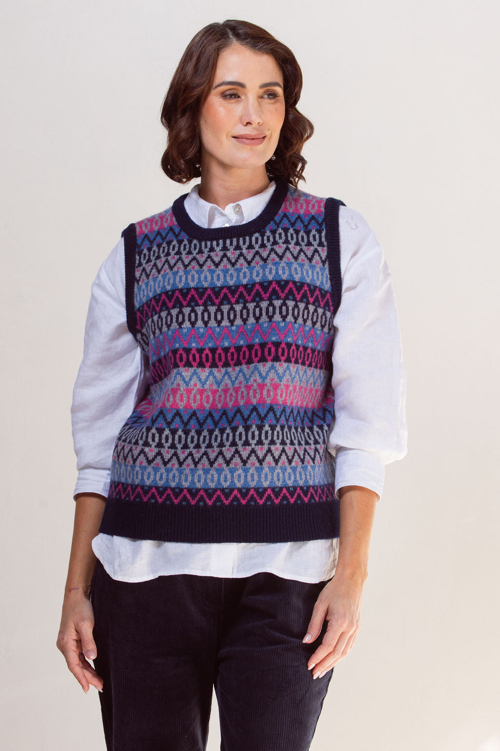 Woman wearing a See Saw jacquard patterned sweater vest over a white shirt on a plain background