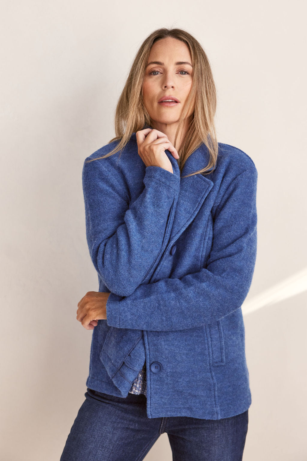Woman wearing green boiled wool See Saw blazer in denim with a white background