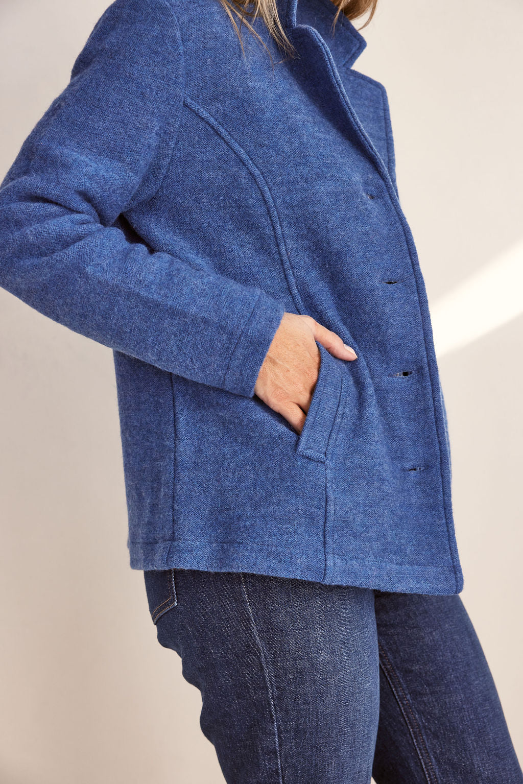 Woman wearing green boiled wool See Saw blazer in denim with a white background