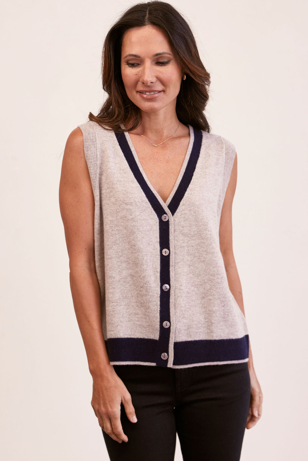 Woman wearing a Merino Wool See Saw beige vest with navy trim in front of a white background